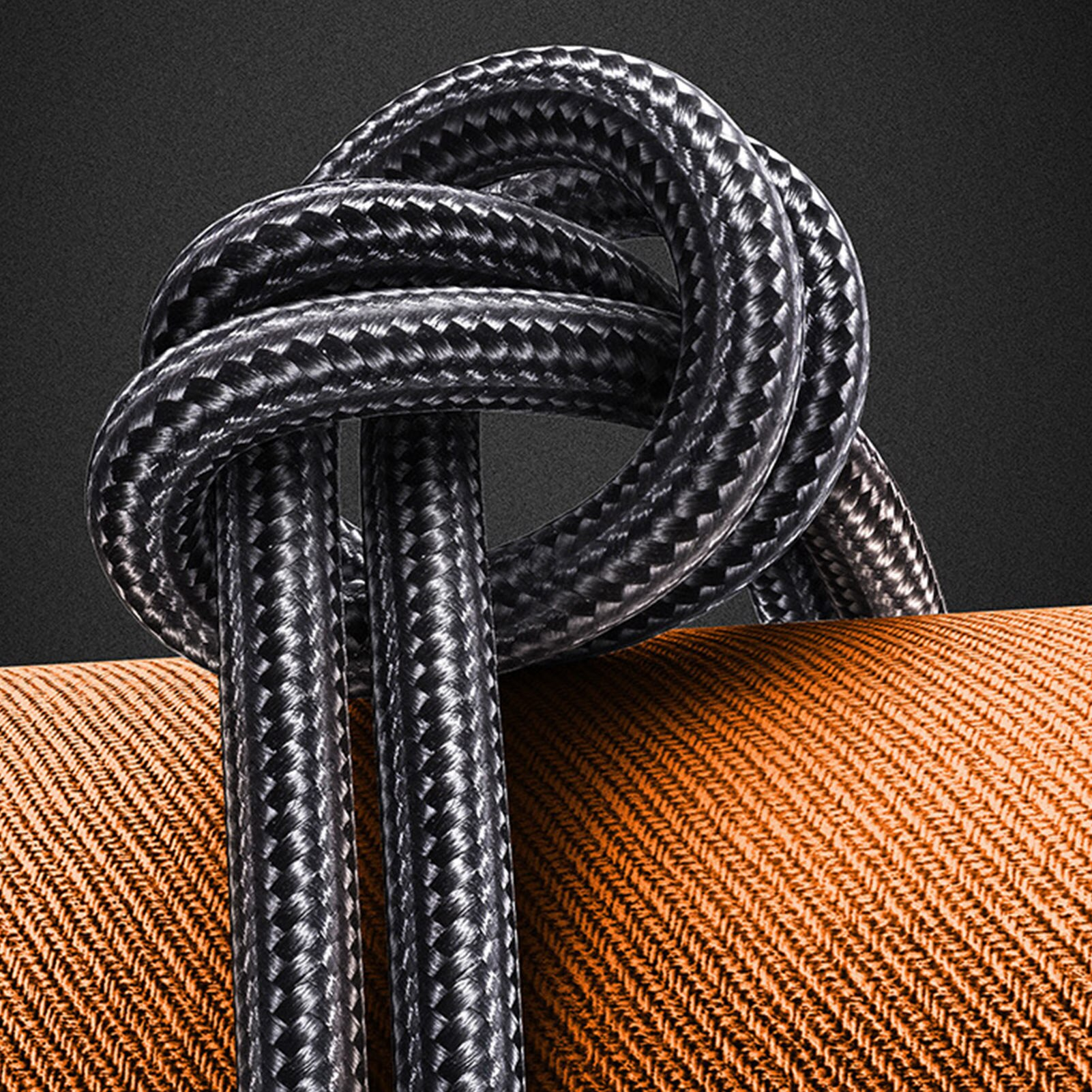 Czarno-szary pleciony kabel na pomarańczowej tkanej powierzchni.
