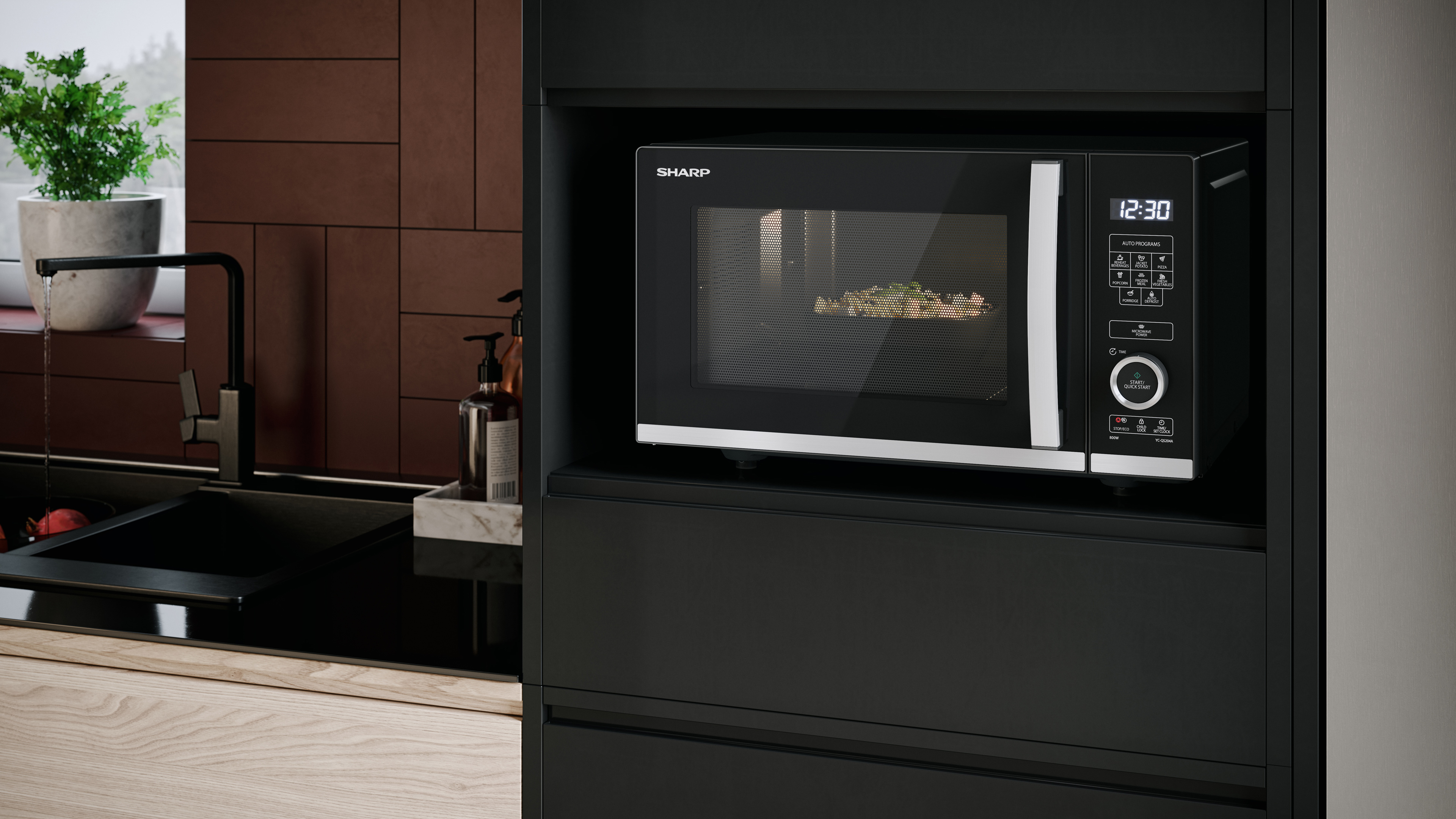 Forno a microonde integrato in un mobile nero. È accanto a un lavandino.
