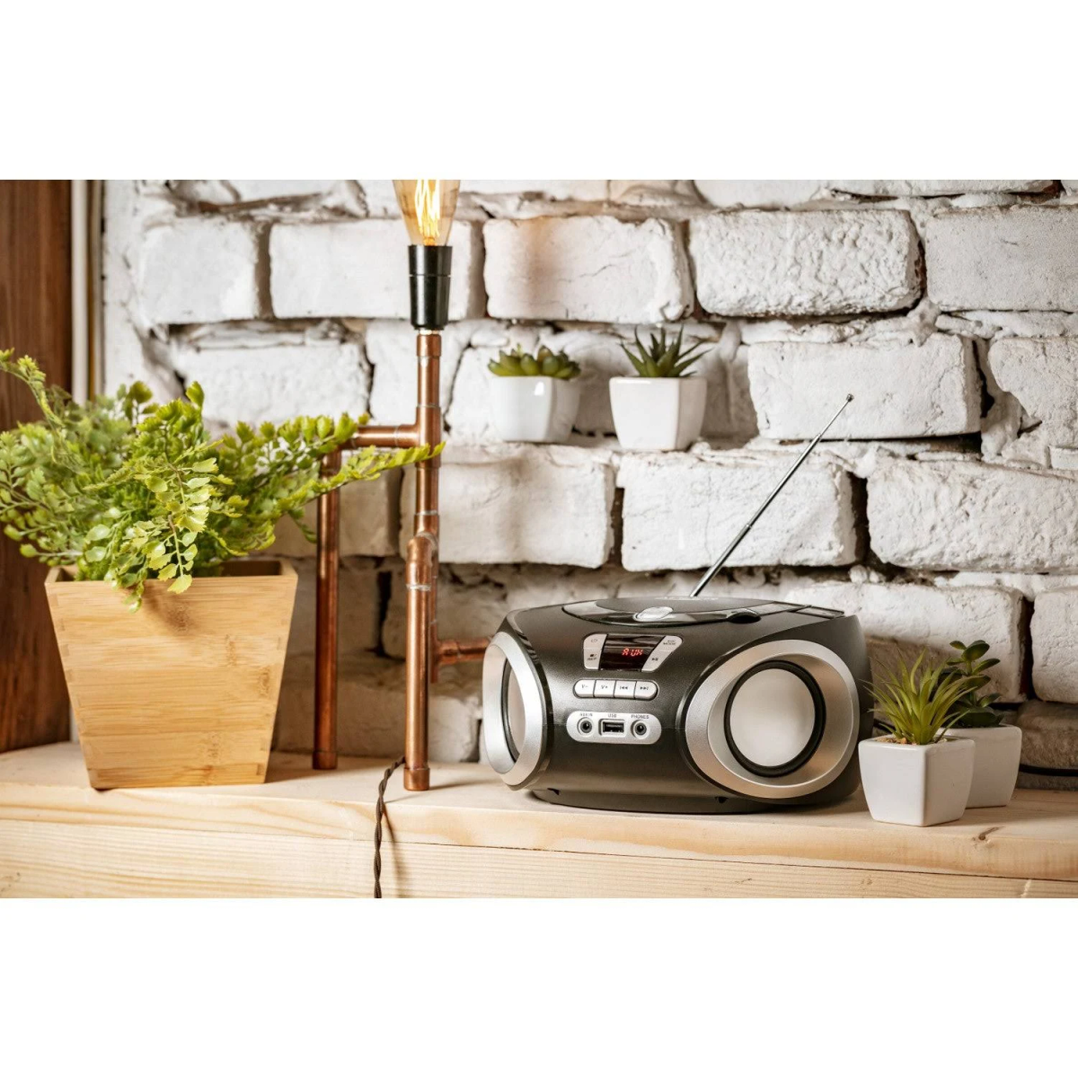 Stereoanlage mit Pflanzen, Lampe und Backsteinmauer im Hintergrund.