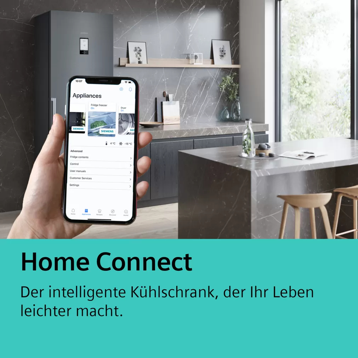 A hand holding a phone showing a smart home app. The background shows a kitchen with a fridge.