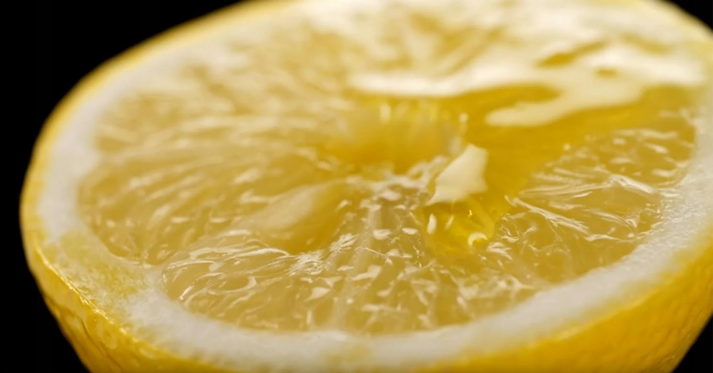 Zbliżenie połówki cytryny. Cytryna jest żółta z widocznymi segmentami i sokiem.