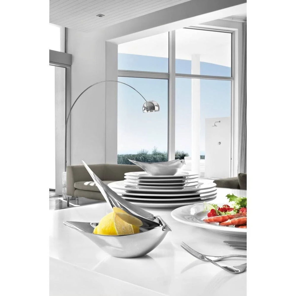 Scena di cucina moderna con uno spremi limoni, piatti e vista sull'esterno.