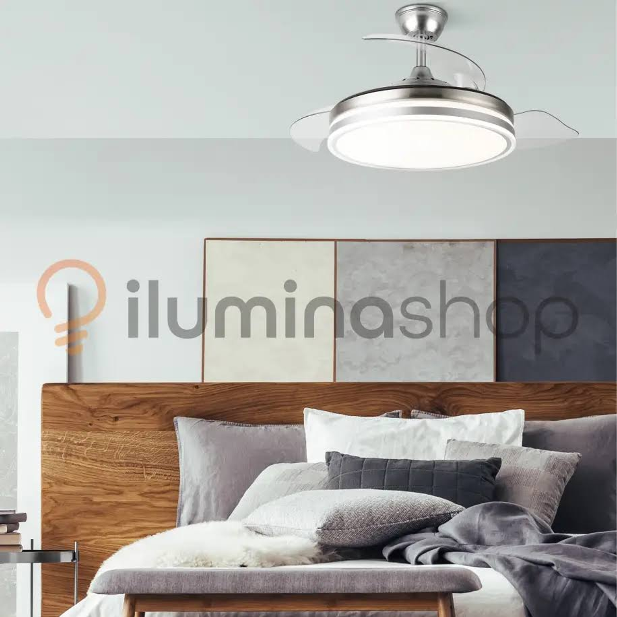 Ventilador de techo sobre una cama, con luz y borde plateado. La cama tiene cabecero de madera.