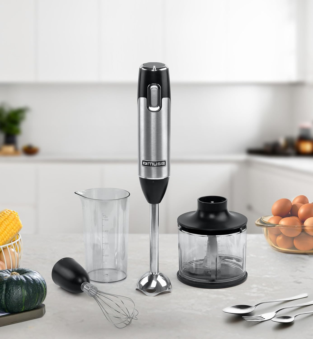 Un frullatore a immersione con accessori: un bicchiere, una frusta e un accessorio per robot da cucina.
