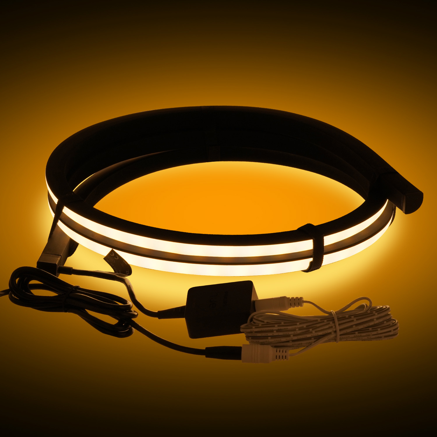 Ein schwarzer LED-Streifen mit gelbem Licht, mit Netzteil und Kabeln.
