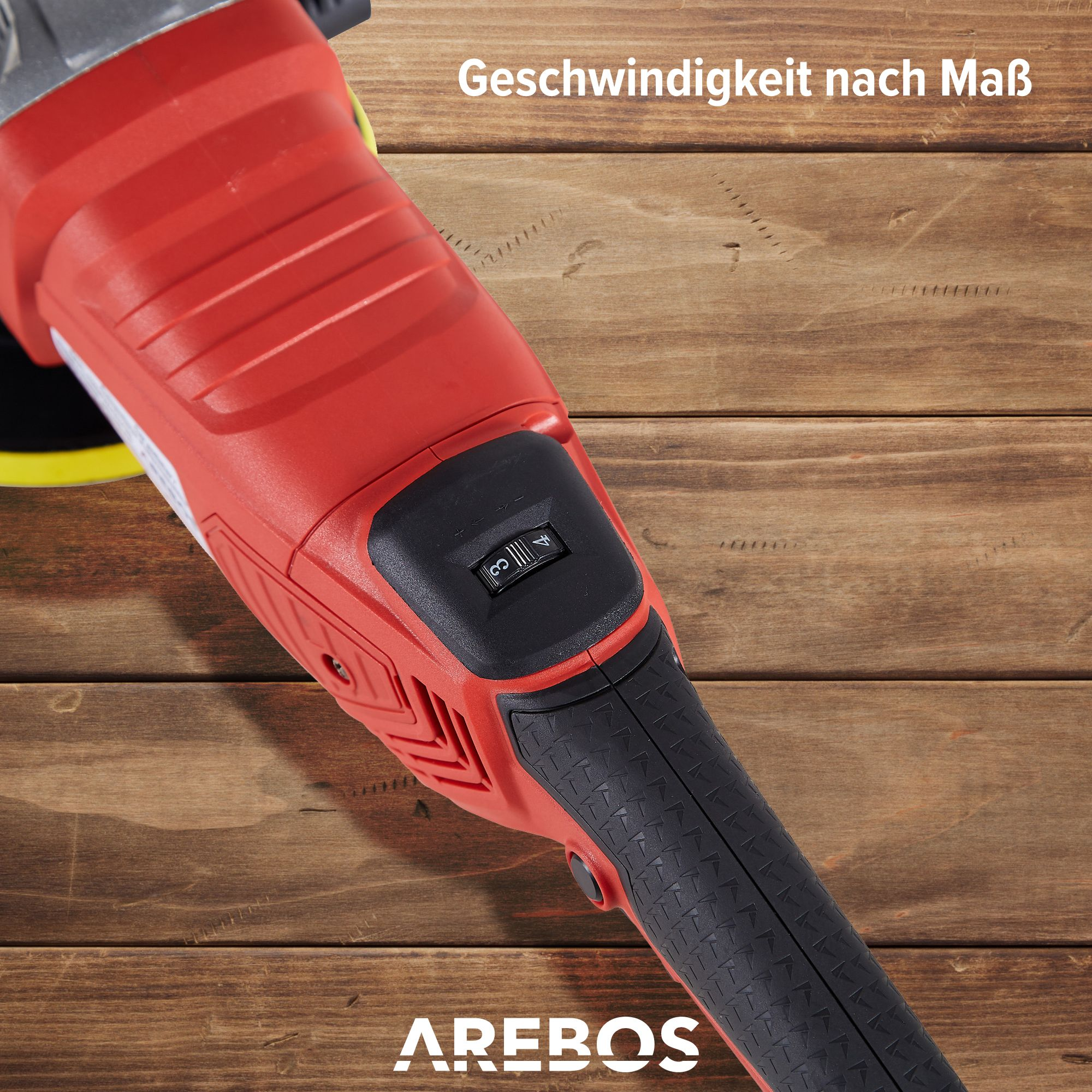Ein roter elektrischer Polierer mit schwarzem Griff, der auf einer Holzoberfläche liegt.