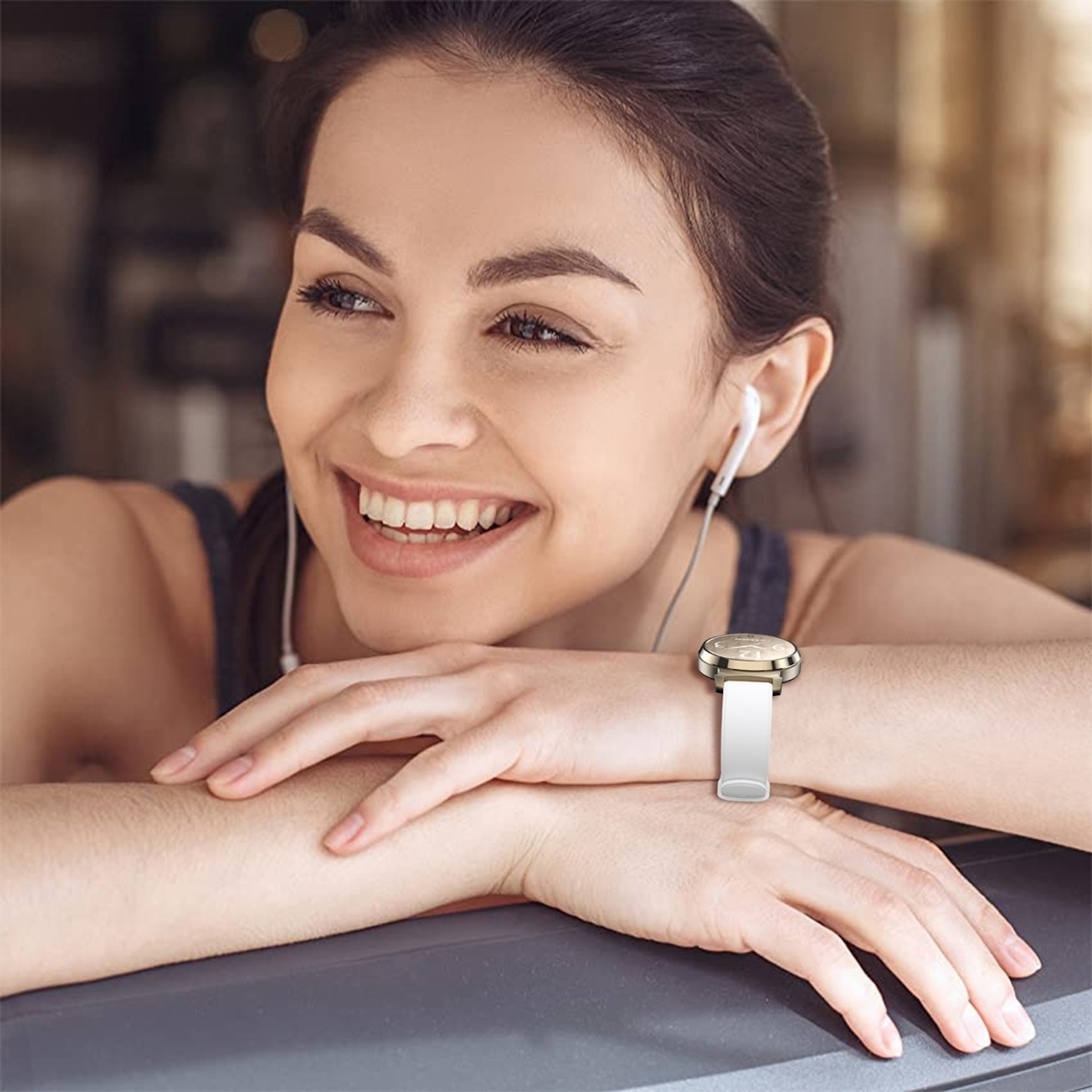 Frau mit einer Smartwatch mit weißem Armband. Sie lächelt, während sie Kopfhörer benutzt.