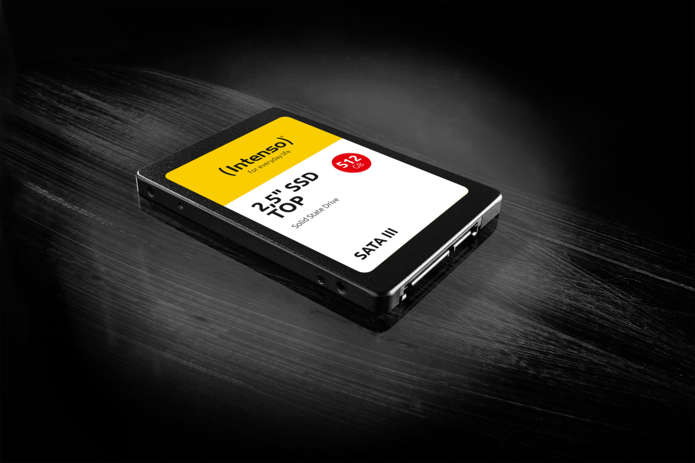 Disque SSD sur une surface sombre. Le disque a une étiquette jaune et blanche.