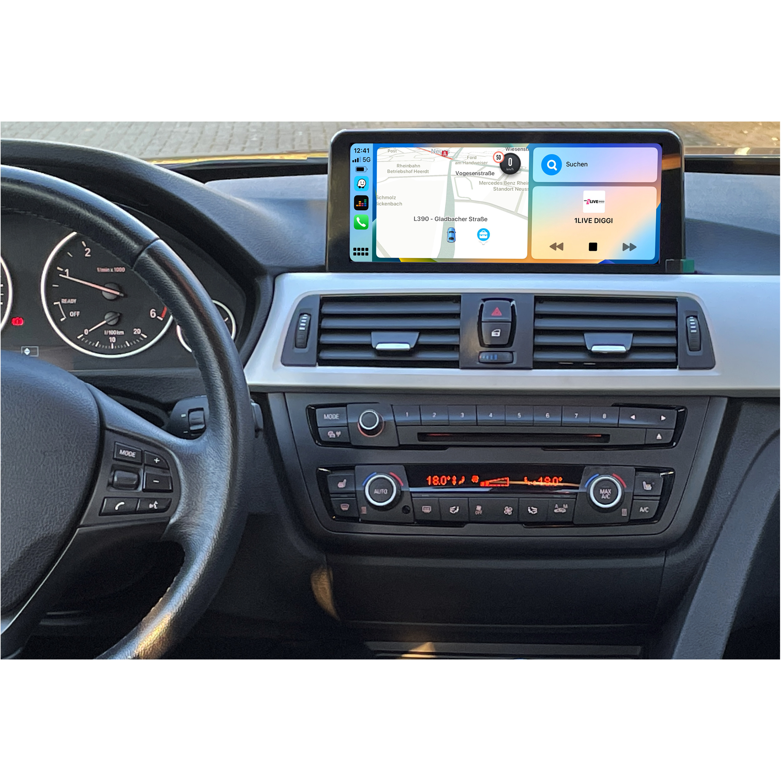 Autointerieur mit Bildschirm, der Navigation anzeigt, umgeben von Knöpfen und Drehreglern.