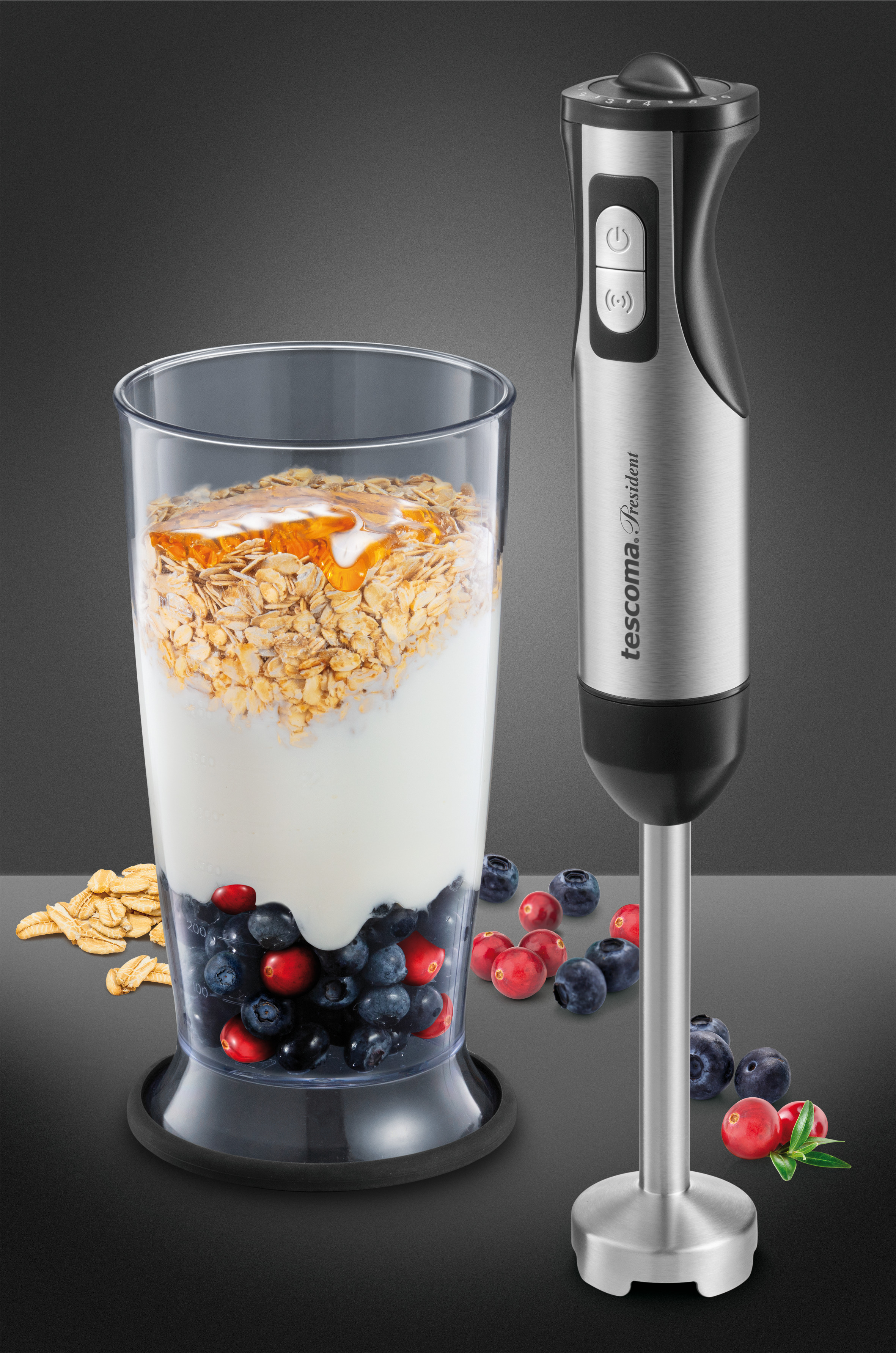 Ein Mixer mit einem Glas gefüllt mit Hafer und Beeren, mit einem Mixer an der Seite, auf dunkler Oberfläche.