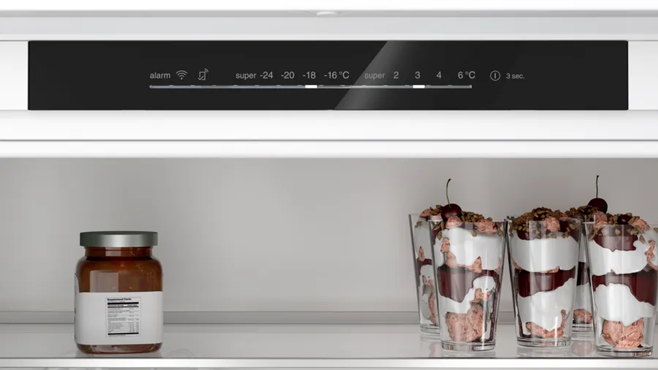 Interior del refrigerador mostrando ajustes, un tarro y parfaits. La pantalla superior muestra ajustes.