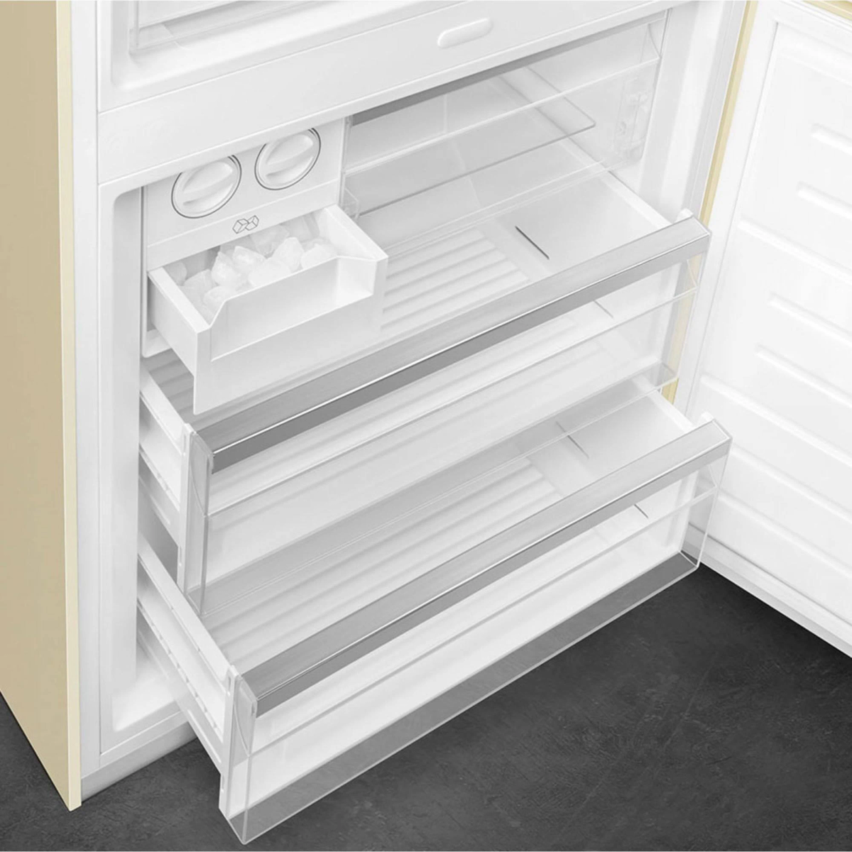 Interior de refrigerador beige con cajones y máquina de hielo. Cajones vacíos y la máquina de hielo abierta.