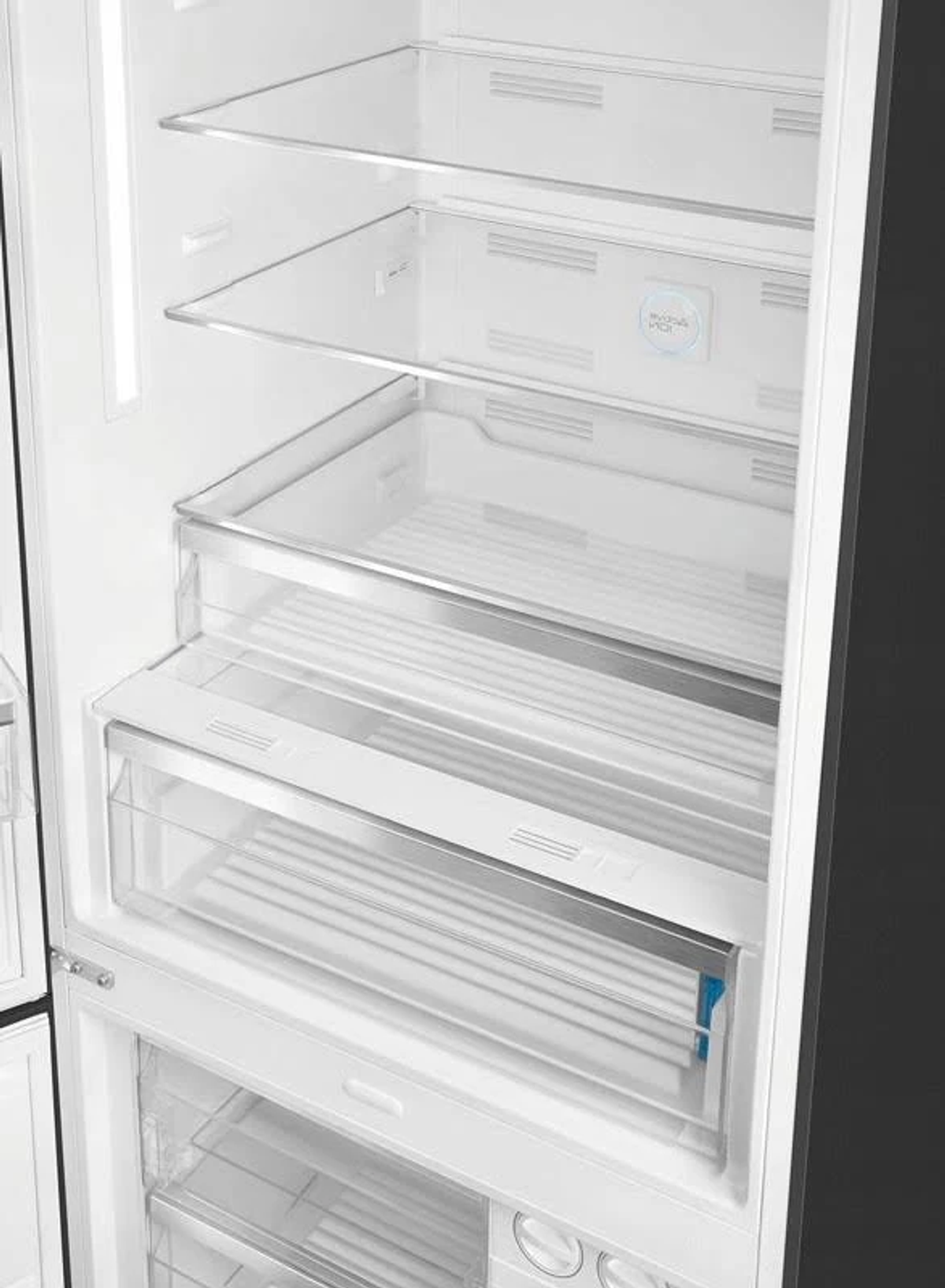 Interior de refrigerador abierto. Estantes y cajones vacíos.