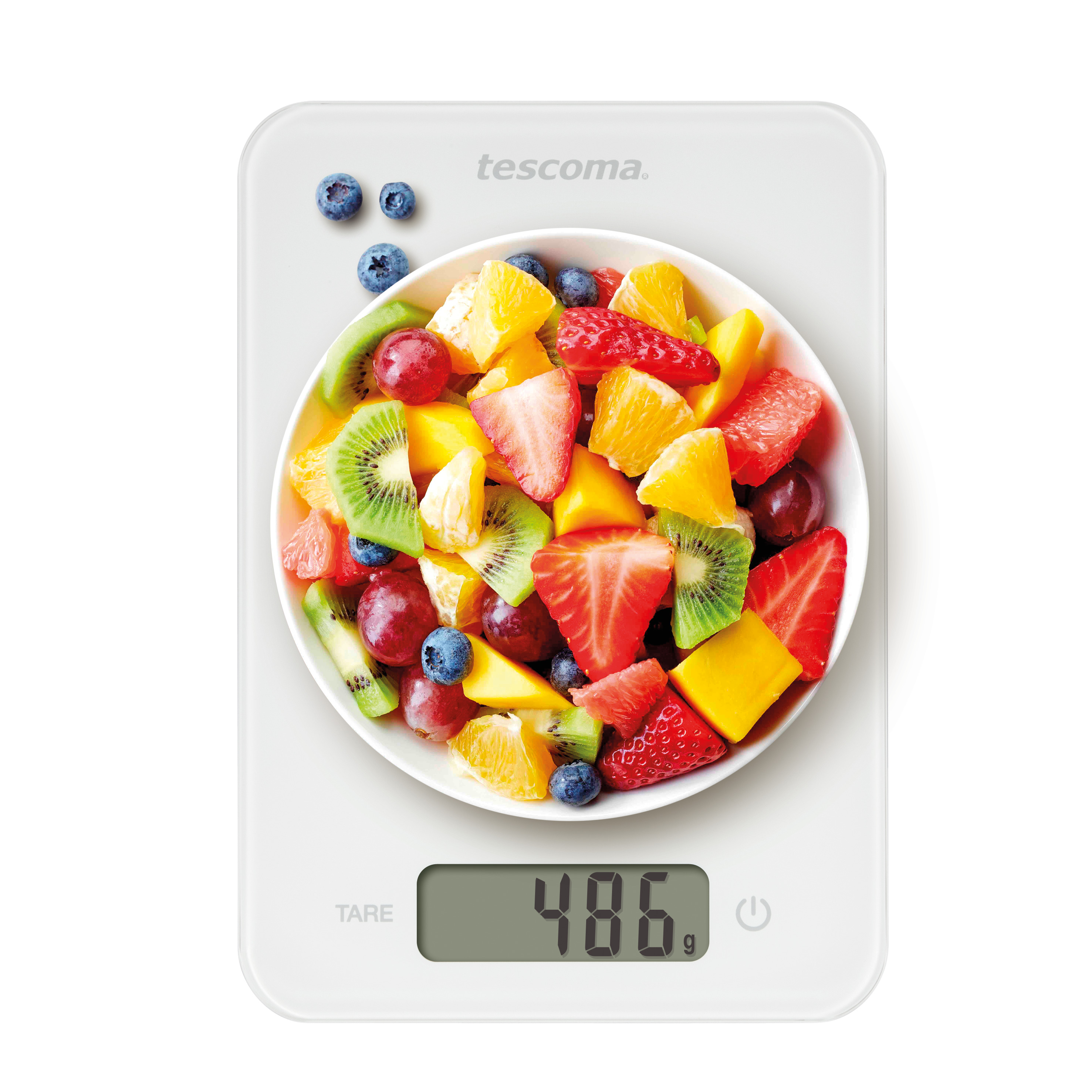 Weiße Küchenwaage mit einer Schüssel mit gemischten Früchten: Erdbeeren, Trauben, Melone, Orangen und Blaubeeren.