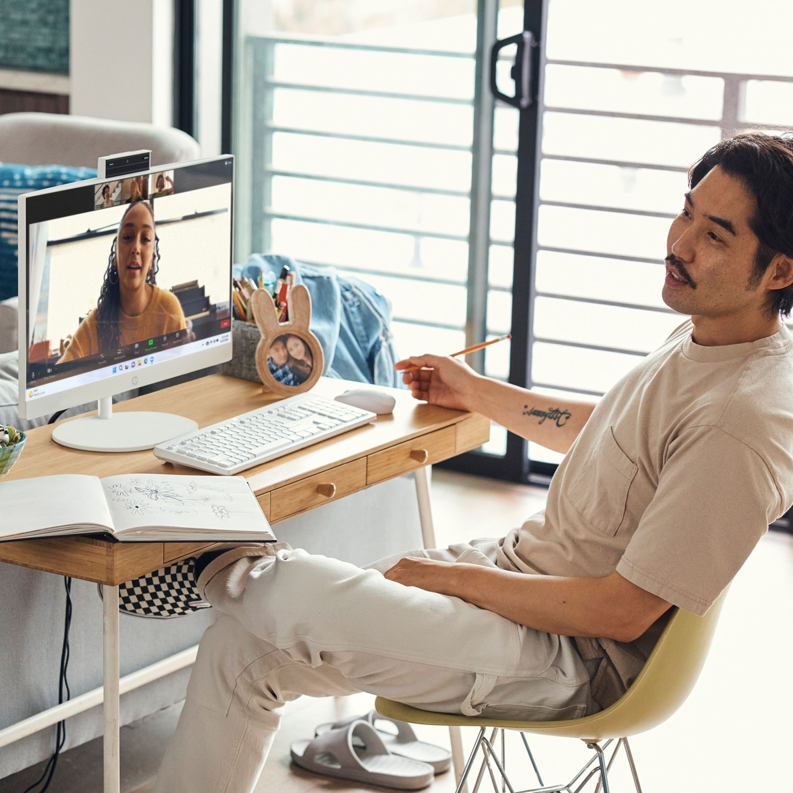 Mężczyzna podczas rozmowy wideo, siedzący przy biurku, z monitorem i notatnikiem przed sobą.