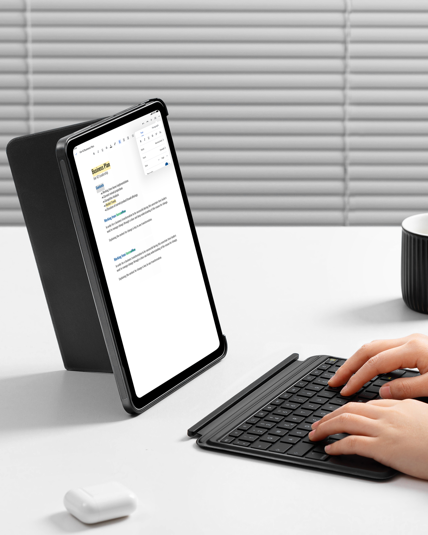 Ein Tablet in einer Hülle, mit einer Tastatur davor aufgestellt. Hände auf der Tastatur.