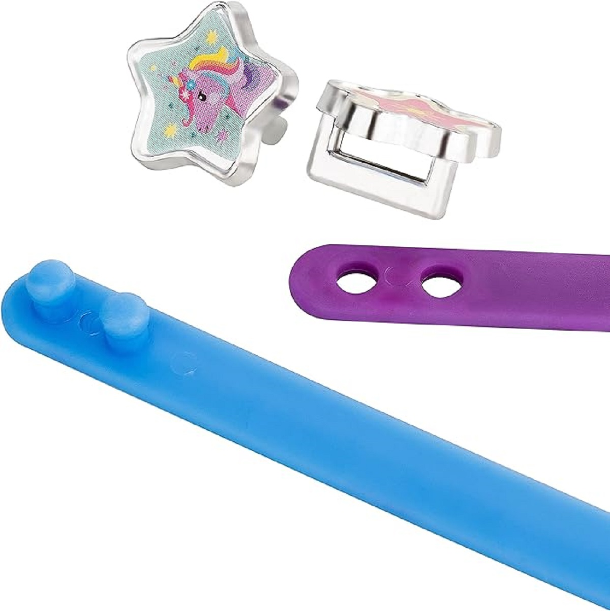 Nahaufnahme von Schmuckstücken: sternförmiger Ring, Einhorn-Ring, blaue und lila Accessoires.