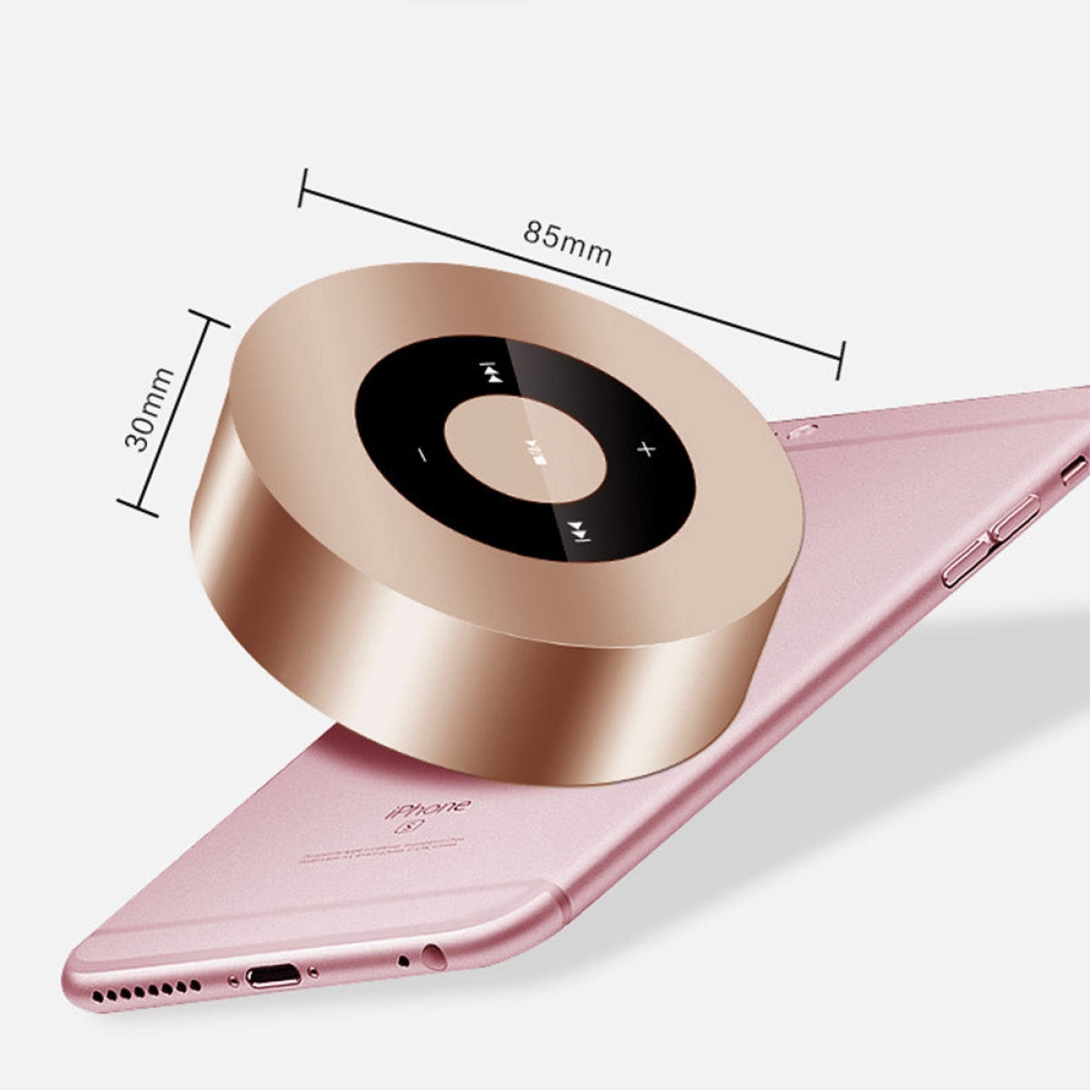 Ein goldfarbener tragbarer Lautsprecher liegt auf einem rosa Telefon. Abmessungen sind angegeben.