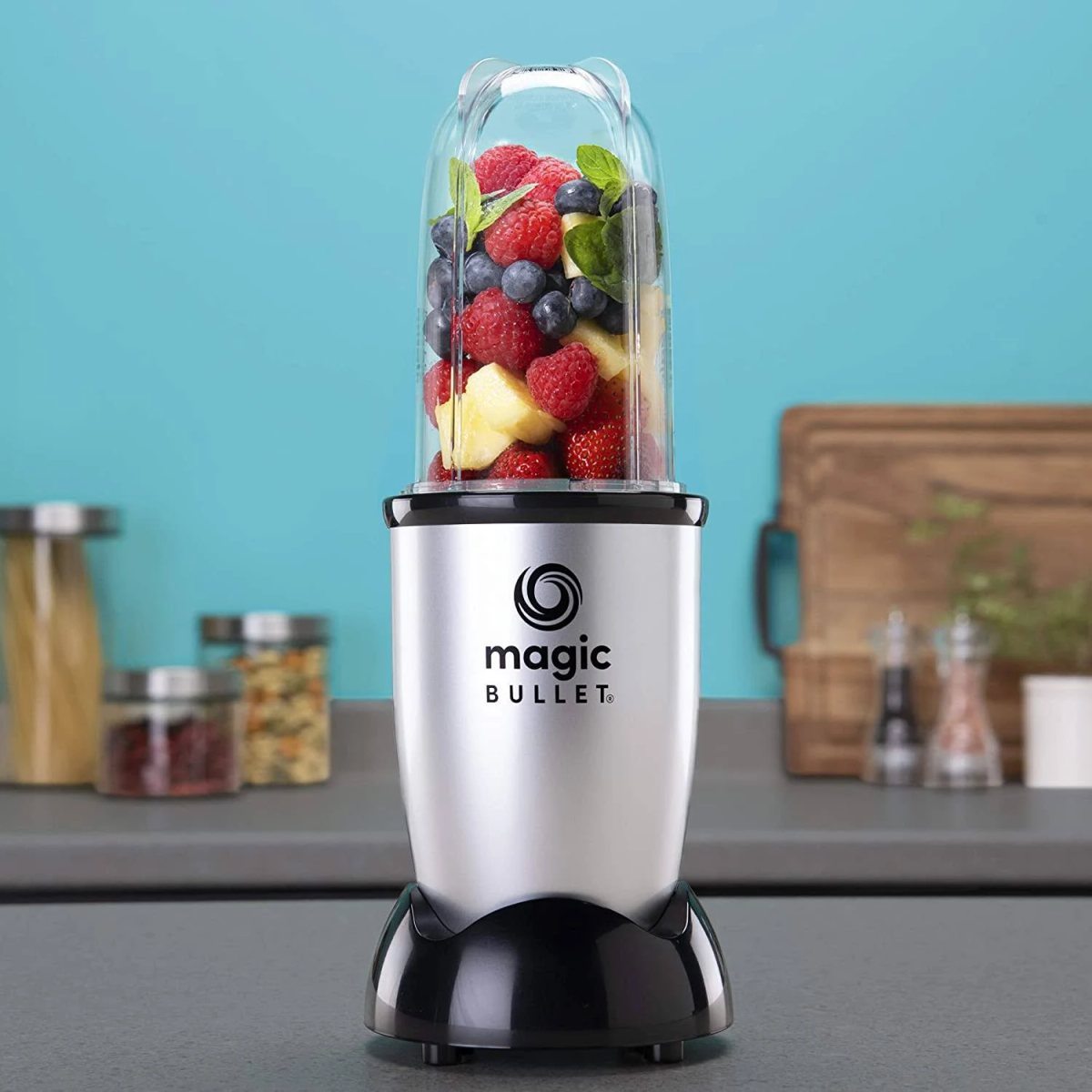Frullatore Magic Bullet argentato con frutta in un contenitore trasparente.