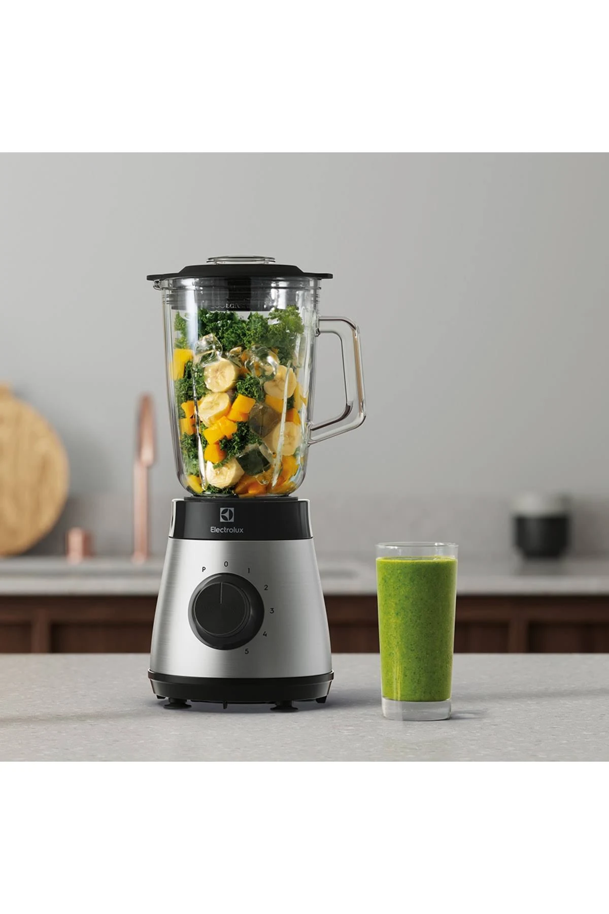 Una licuadora Electrolux con ingredientes y un batido verde.