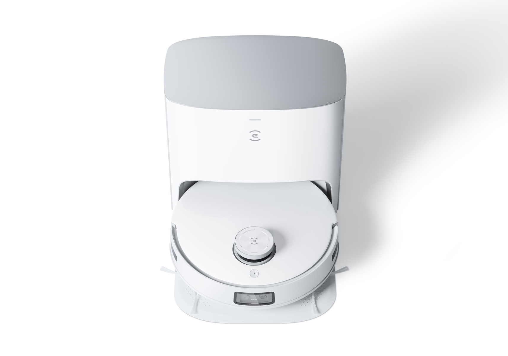Weißer Roboter-Staubsauger auf weißer Oberfläche. Er hat einen grauen Deckel und eine Ladestation.