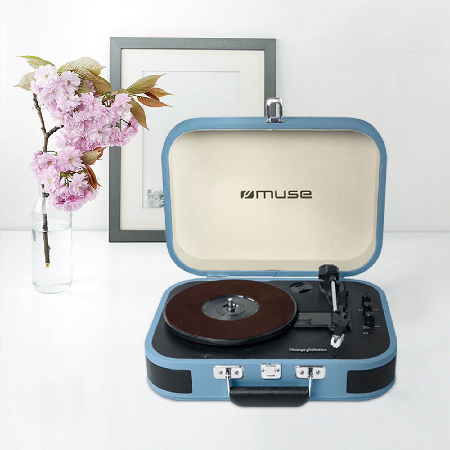 Een blauwzwarte vintage platenspeler met een plaat erop, met bloemen.