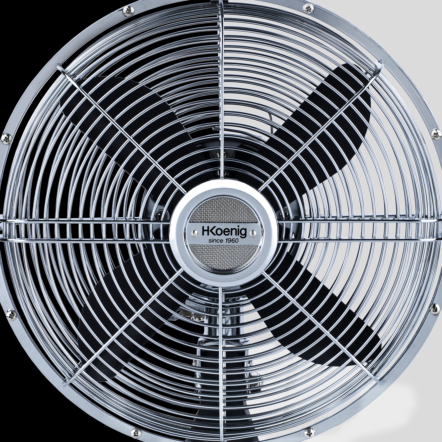 Primo piano di un ventilatore. Griglia cromata circolare con pale visibili. Il marchio è al centro.