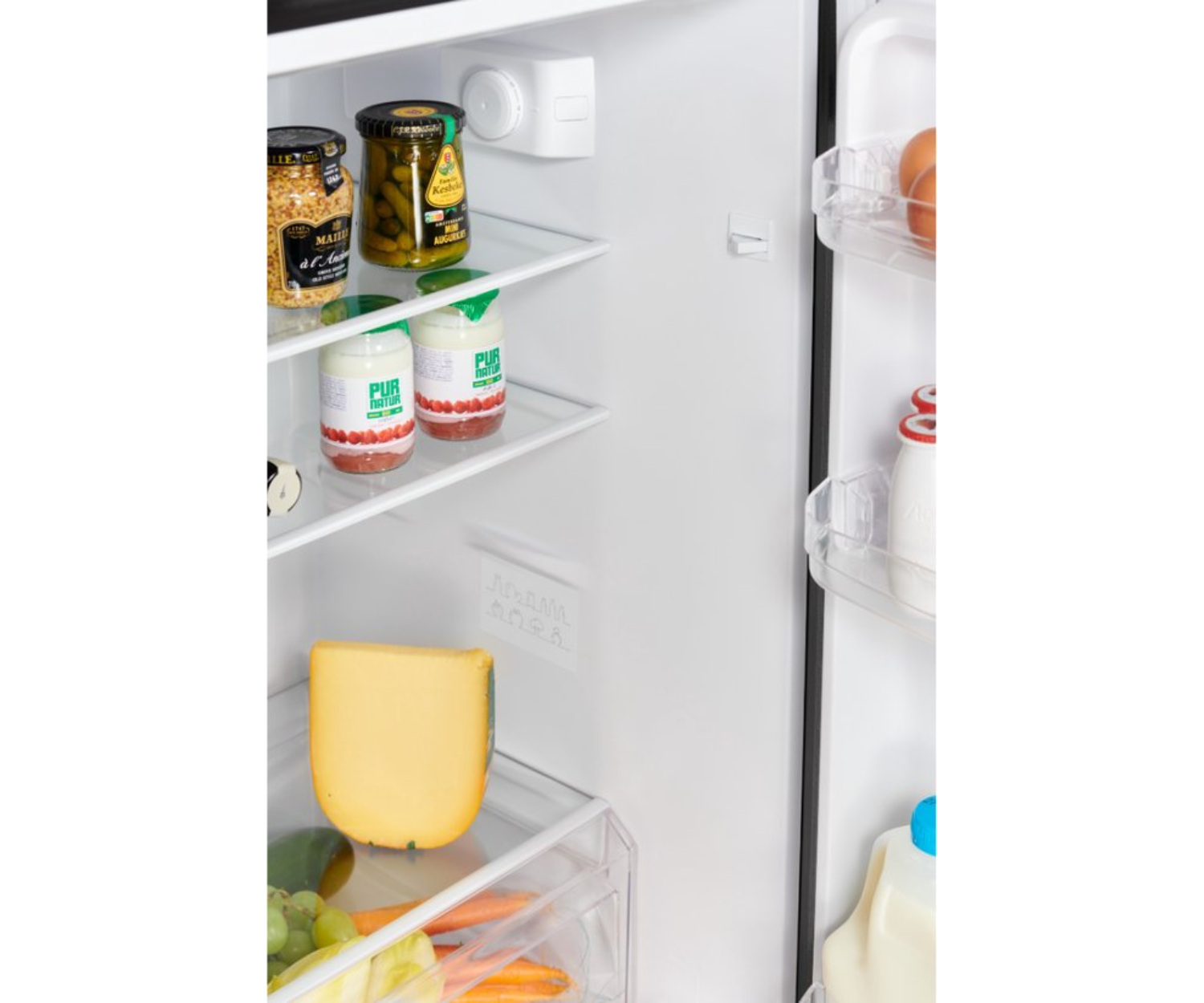 Gros plan de l'intérieur du réfrigérateur avec des bocaux de cornichons, de la mayonnaise, du fromage et des raisins sur les étagères.