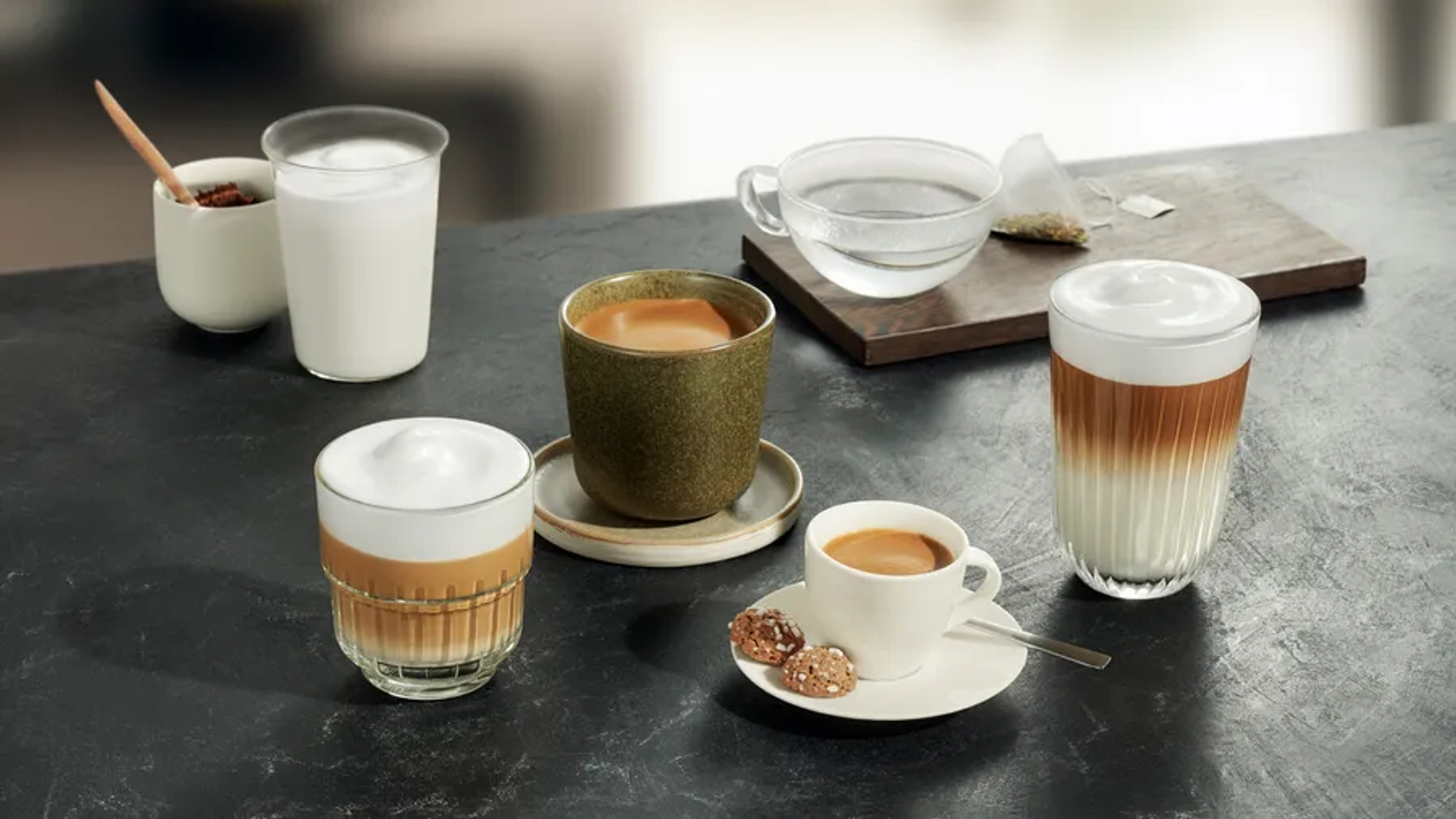 Różne napoje kawowe na ciemnej powierzchni, w tym latte i espresso.