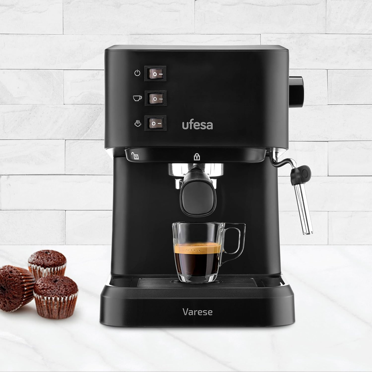 Máquina de espresso Ufesa negra, con una taza de café de vidrio y tres muffins.