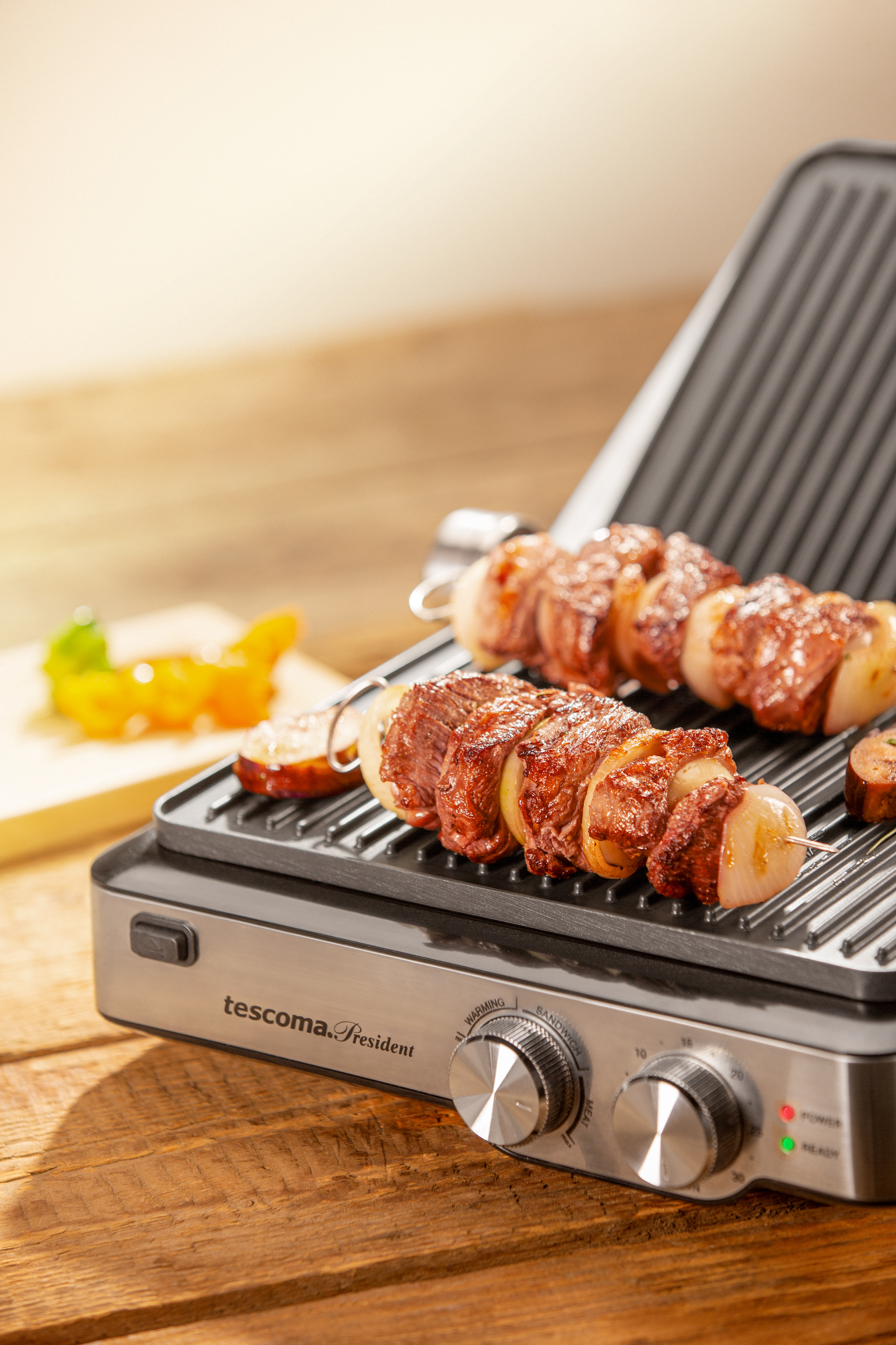 Ein Grill mit gekochten Kebabs und Würstchen auf einem Holztisch.