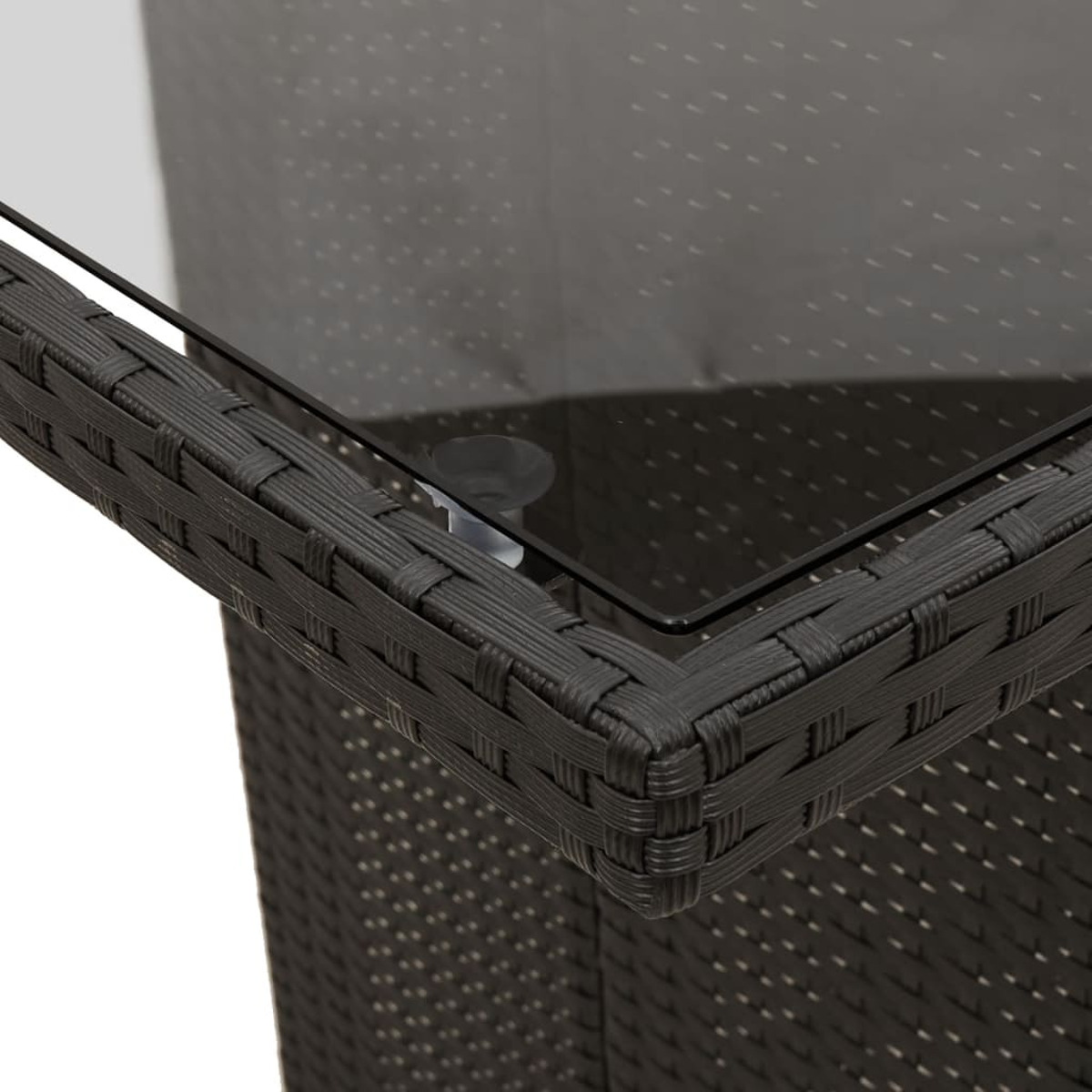 Un primo piano di un tavolo nero intrecciato. Il tavolo ha un piano in vetro e uno sfondo scuro.