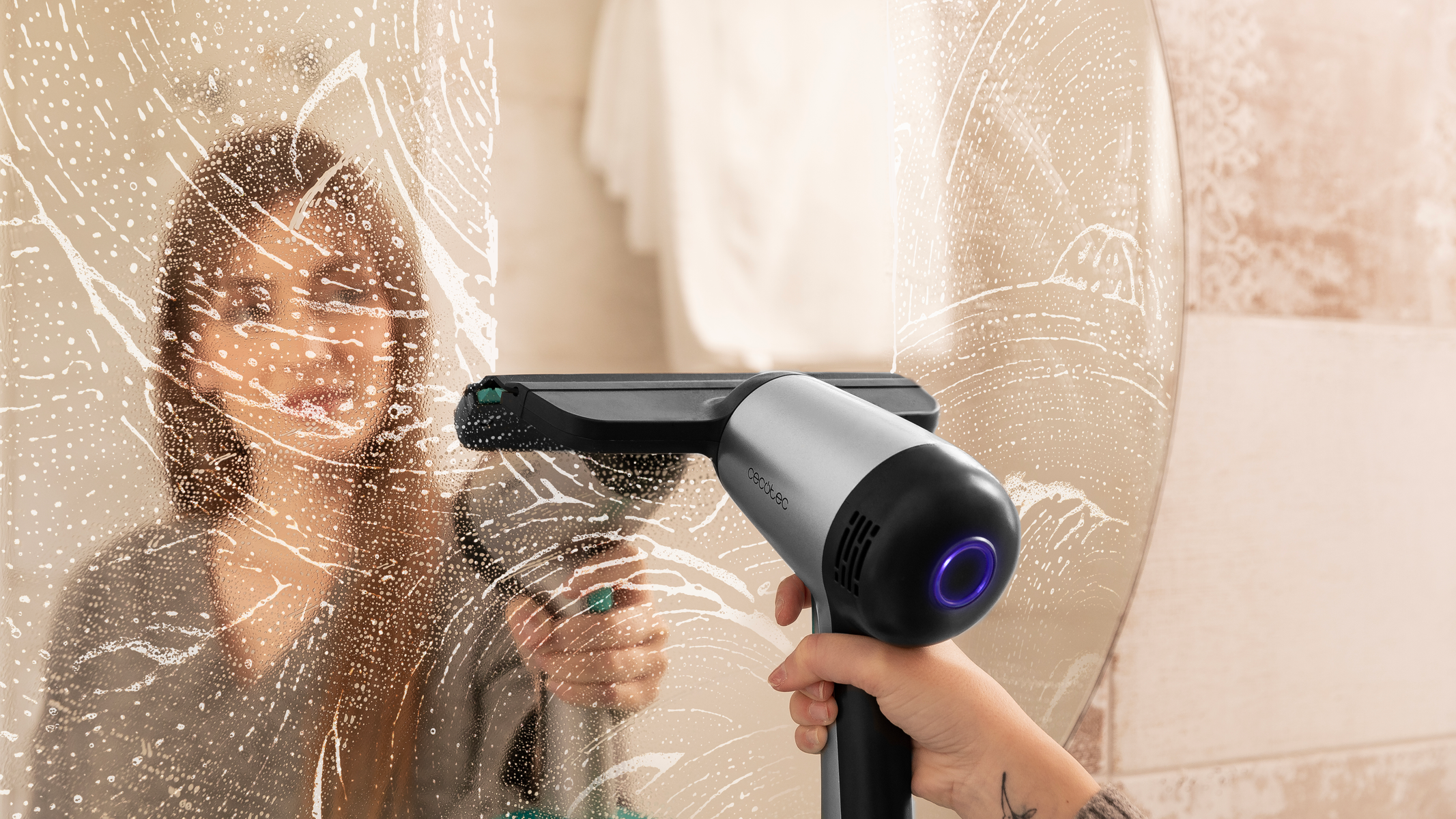 Donna che pulisce uno specchio con un detergente per vetri, con riflesso sfocato visibile.