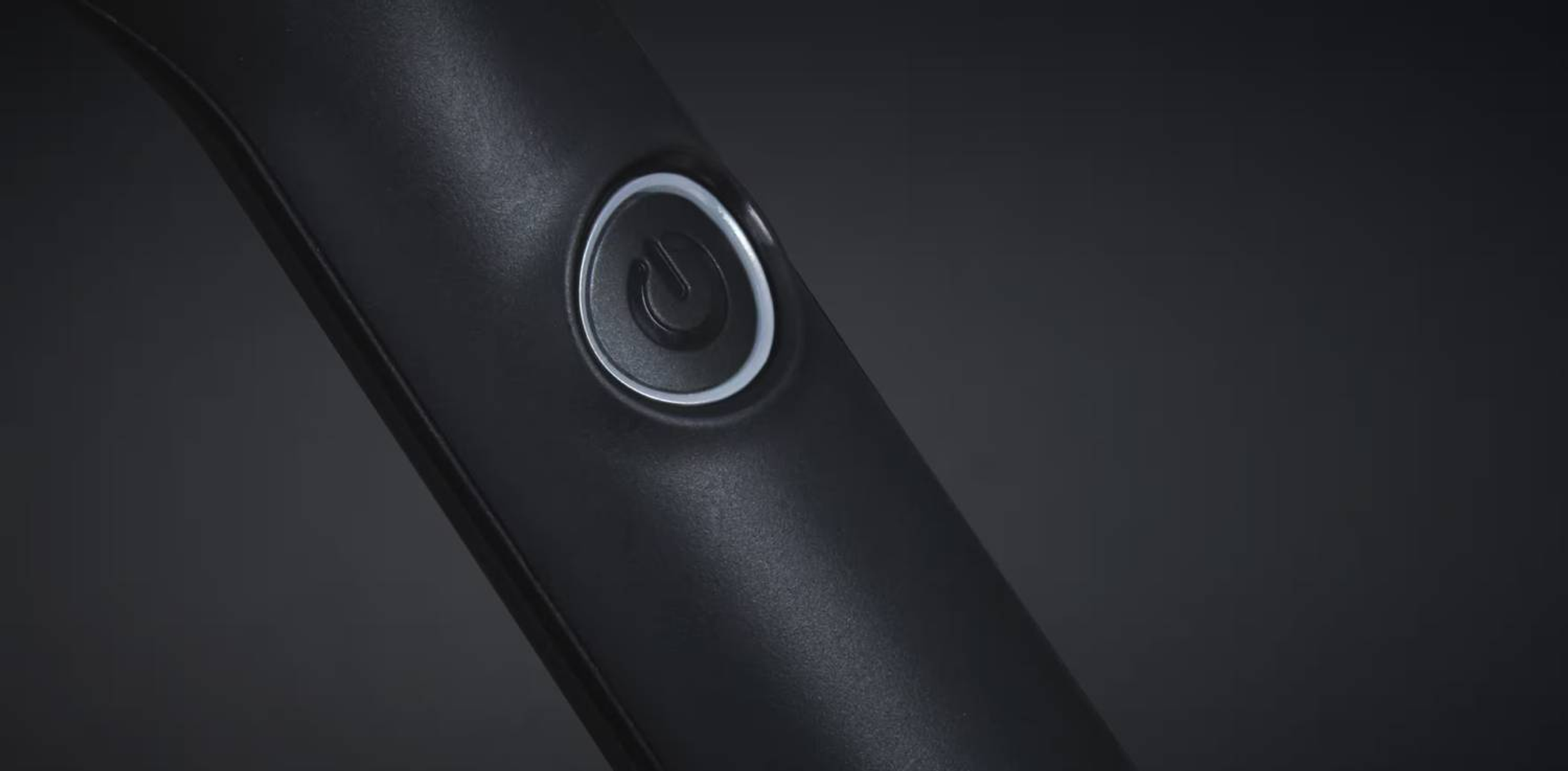 Primer plano de un botón de encendido negro con un contorno blanco en un mango negro curvado.