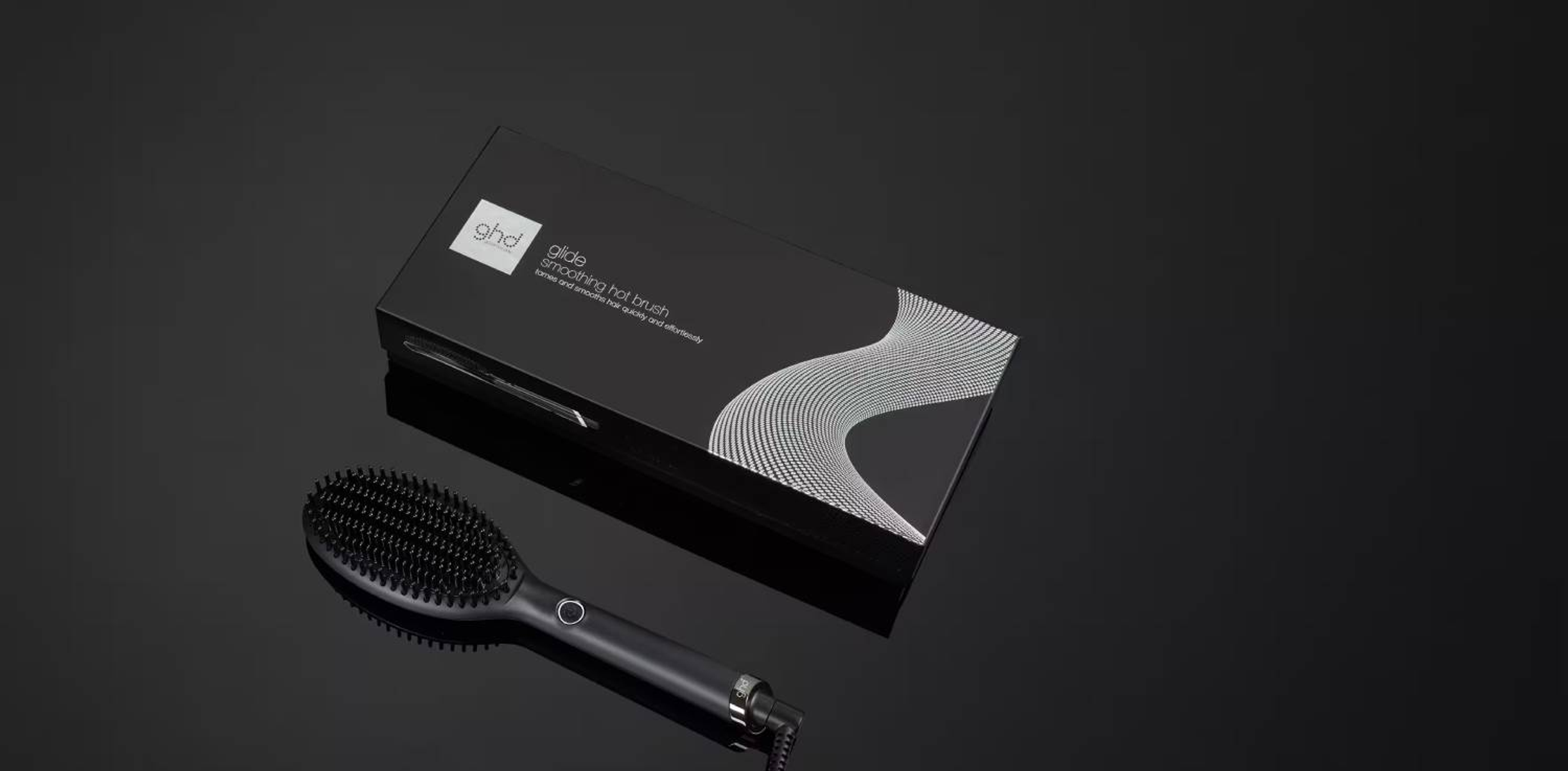 Cepillo alisador GHD Glide y su embalaje en superficie reflectante.