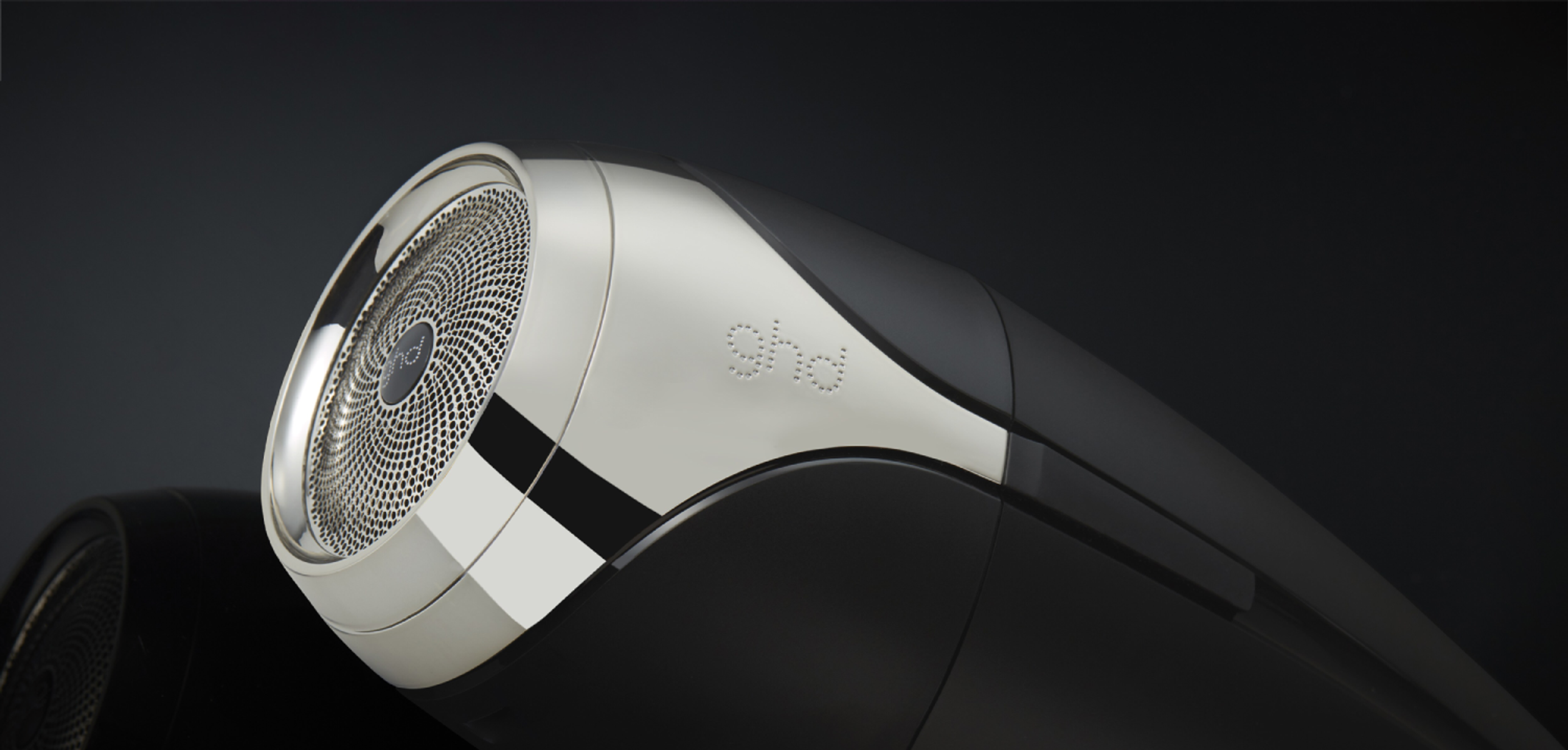 Primer plano de un secador de pelo negro y plateado con la marca 'ghd'.