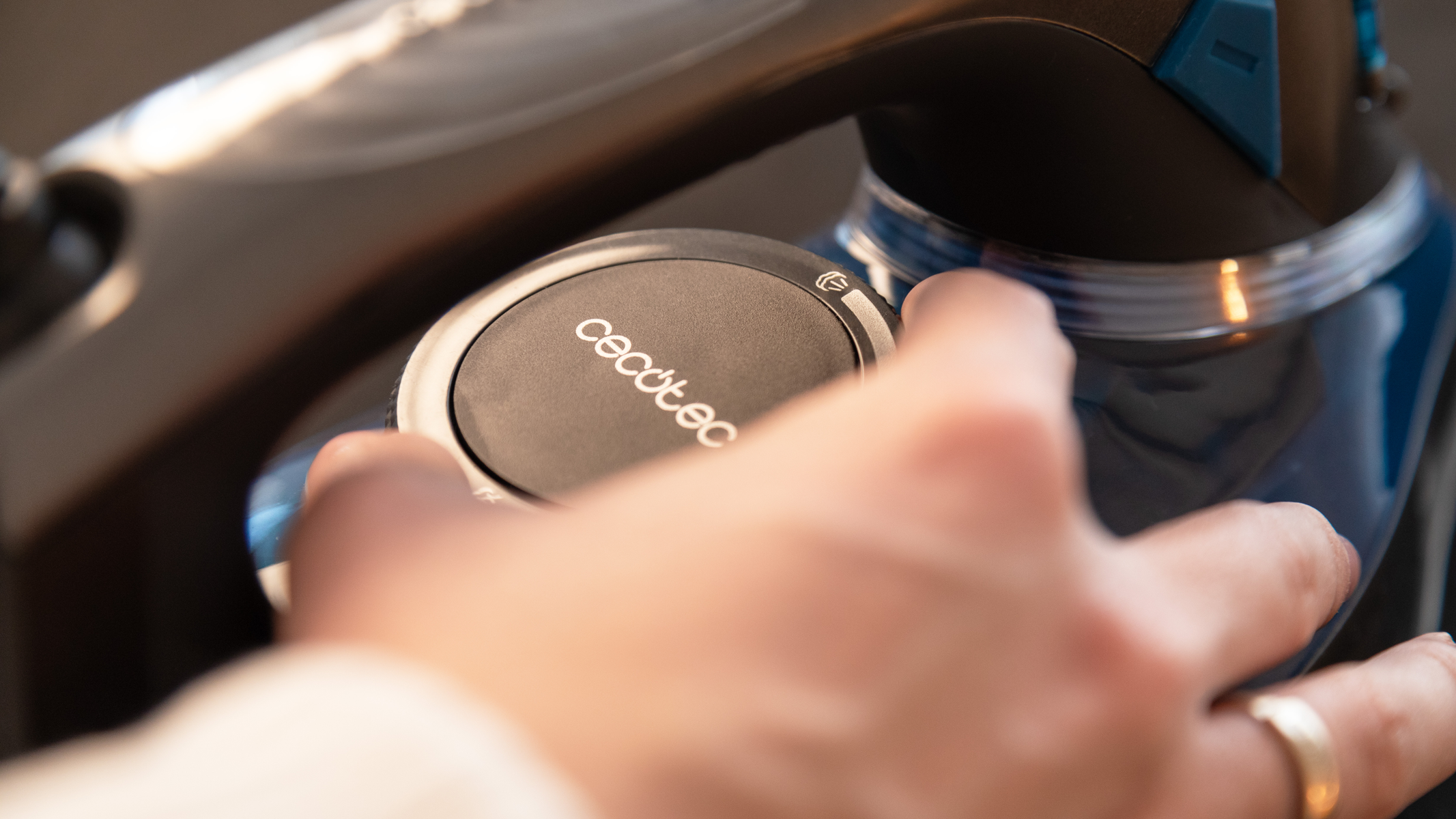 Hand adjusting a black and silver vacuum cleaner dial with 'cecotec' written on it.