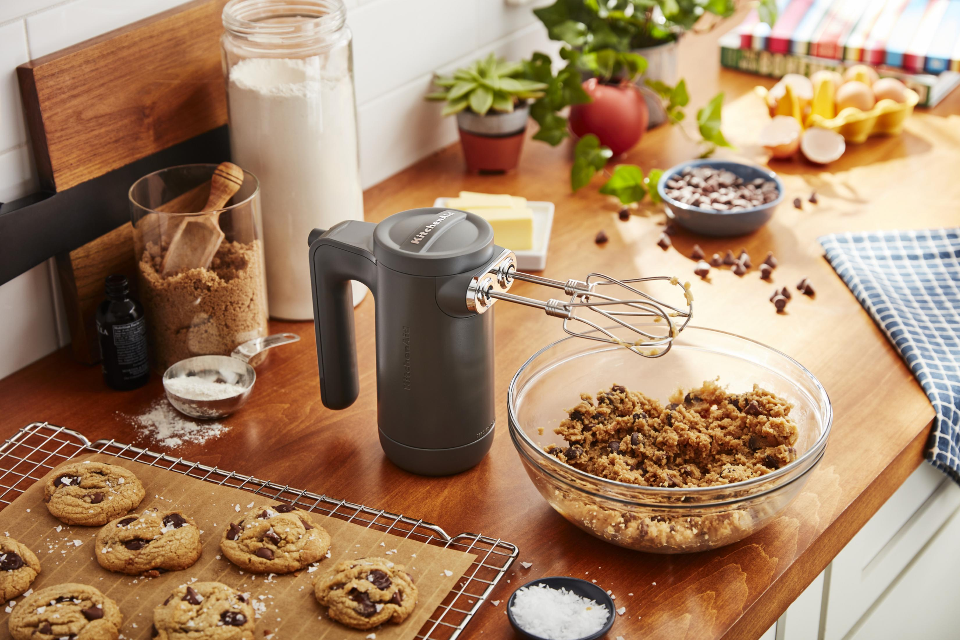 KitchenAid el mikseri, kurabiye hamuru dolu kase ve ahşap masada kurabiye malzemeleri.