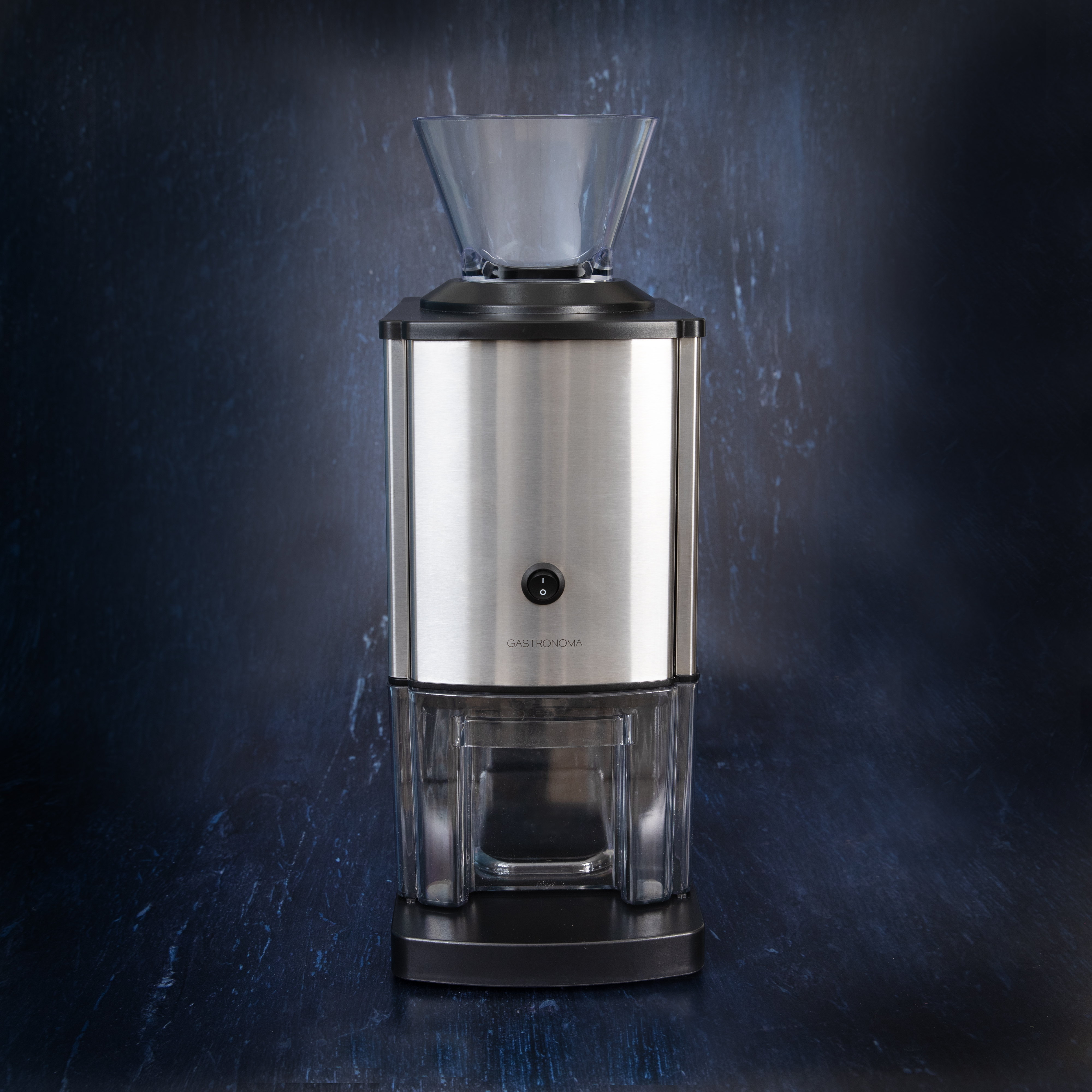 Kaffeemühle aus Edelstahl und Schwarz mit transparentem Trichter, schwarzem Sockel und dunklem Hintergrund.