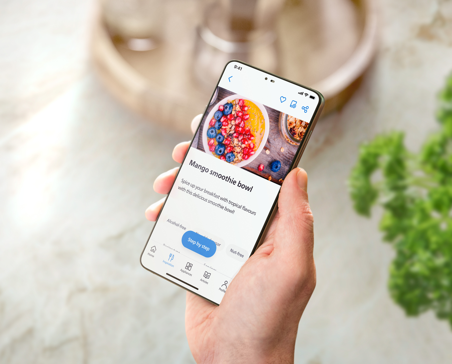Osoba trzymająca telefon wyświetlający przepis na miskę z mango smoothie.
