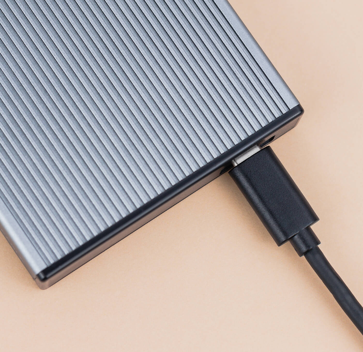 Zbliżenie srebrnego, żebrowanego, prostokątnego zewnętrznego dysku twardego z kablem USB-C.