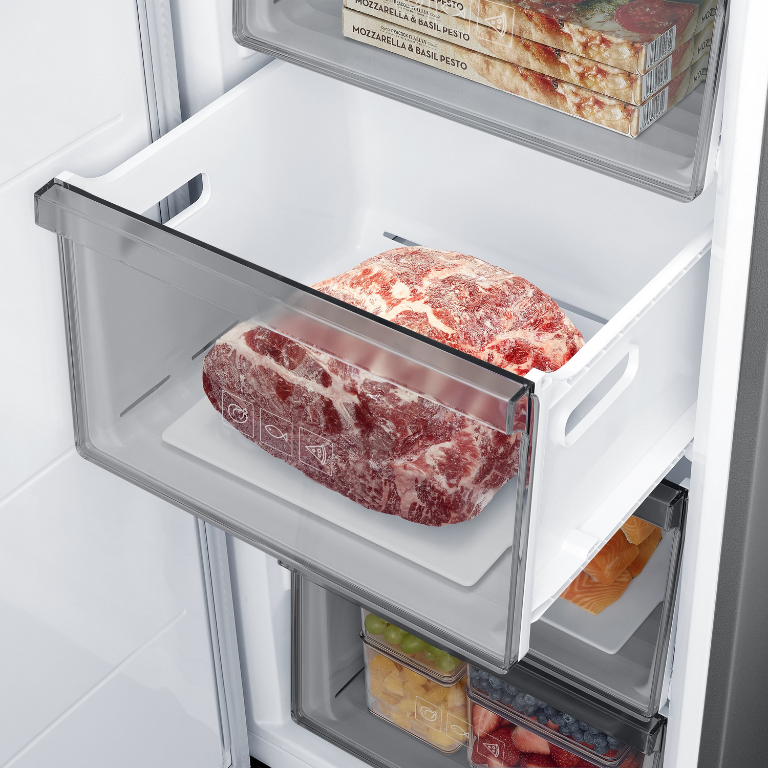 Dentro de un refrigerador, dos cajones exhiben carne congelada y otros artículos.