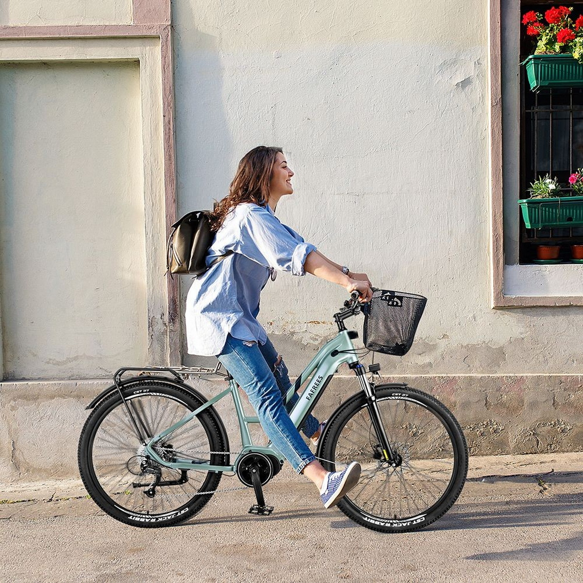 Eine Frau fährt mit einem hellblauen Fahrrad mit Korb. Sie trägt ein hellblaues Hemd.