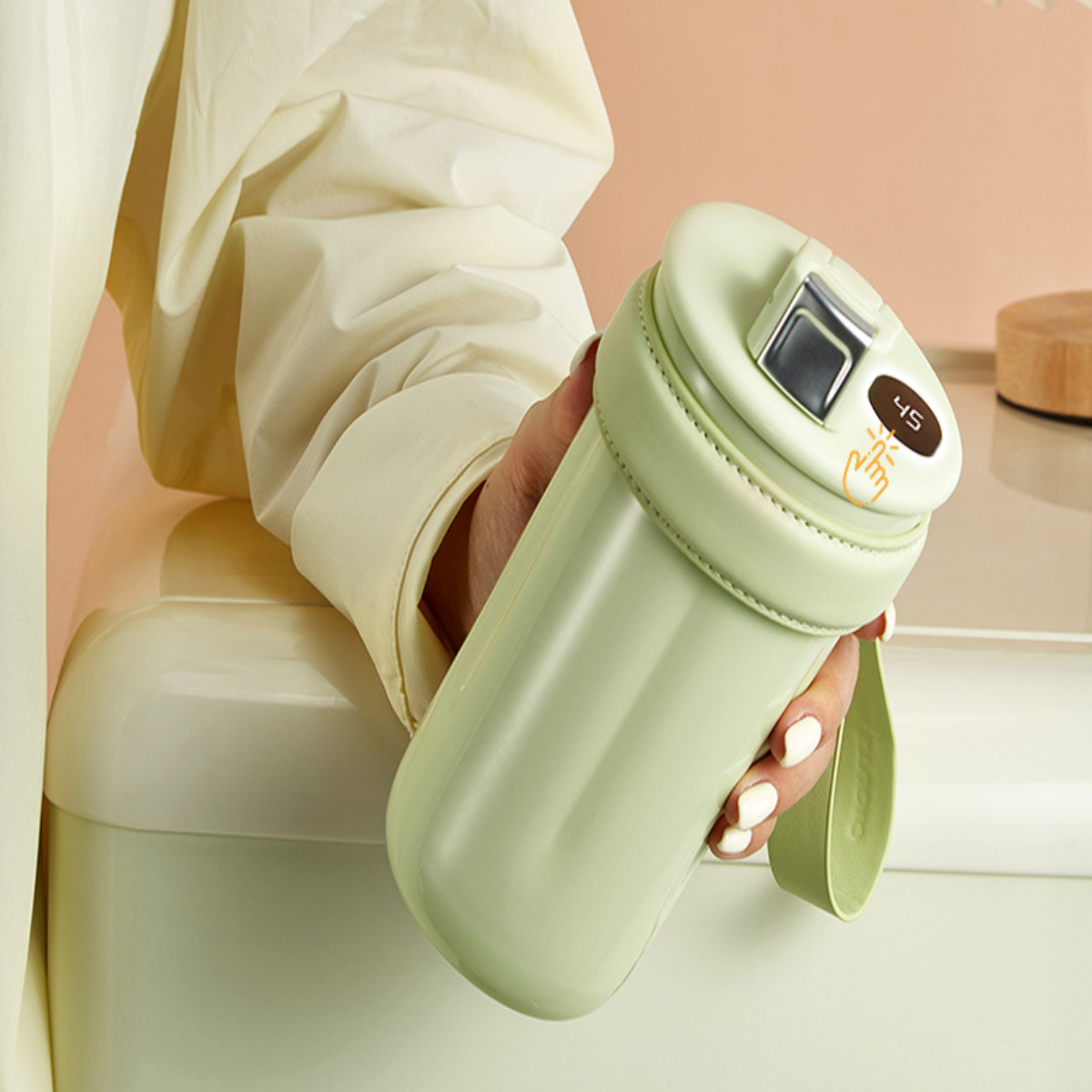 Eine Hand hält eine grüne Wasserflasche mit digitaler Temperaturanzeige oben.