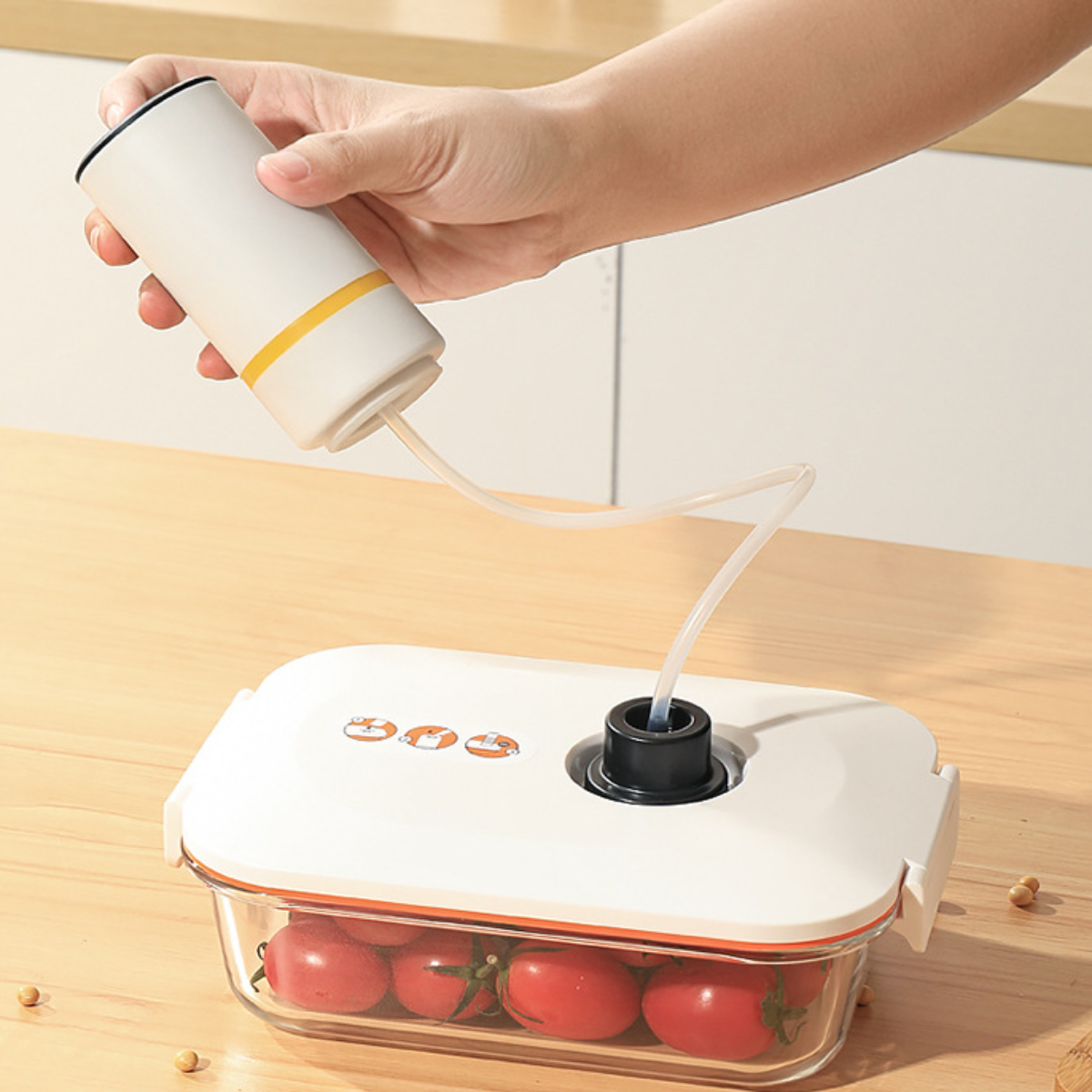 Eine Hand, die einen Behälter mit Tomaten darin vakuumversiegelt, auf weißem Hintergrund.
