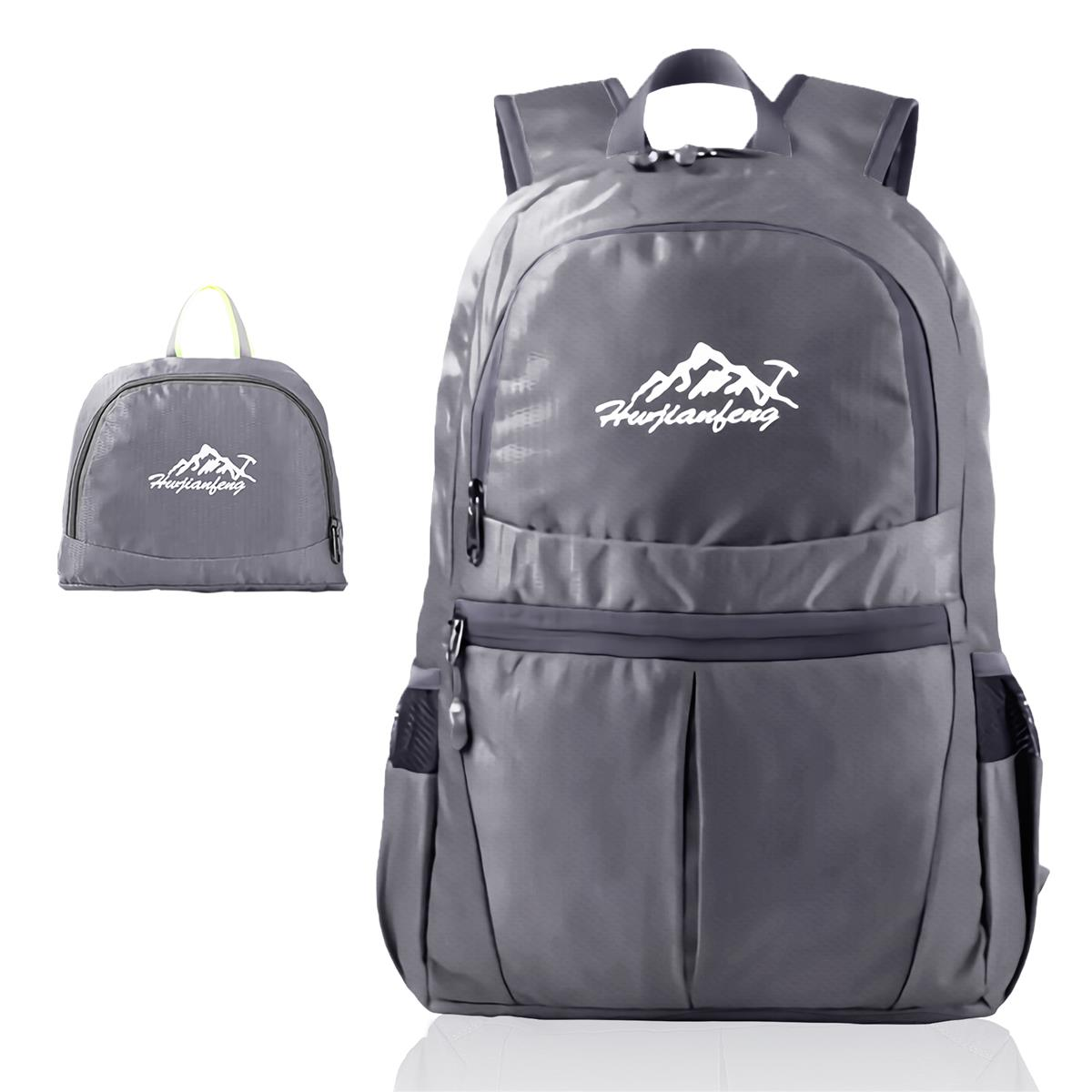 Grauer Rucksack mit kleinerer zusammengefalteter Tasche. Der Rucksack hat ein Berglogo.