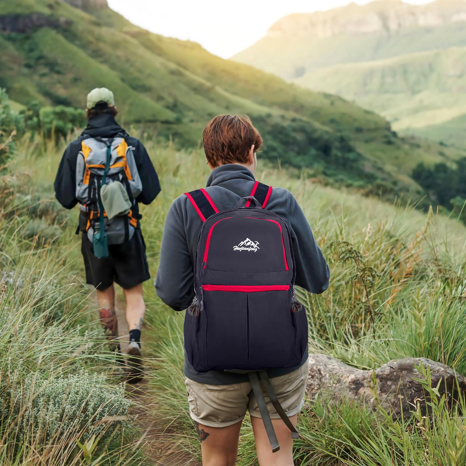 Zwei Wanderer auf einem Bergpfad. Einer trägt einen Rucksack, der andere Rucksack und Hut.