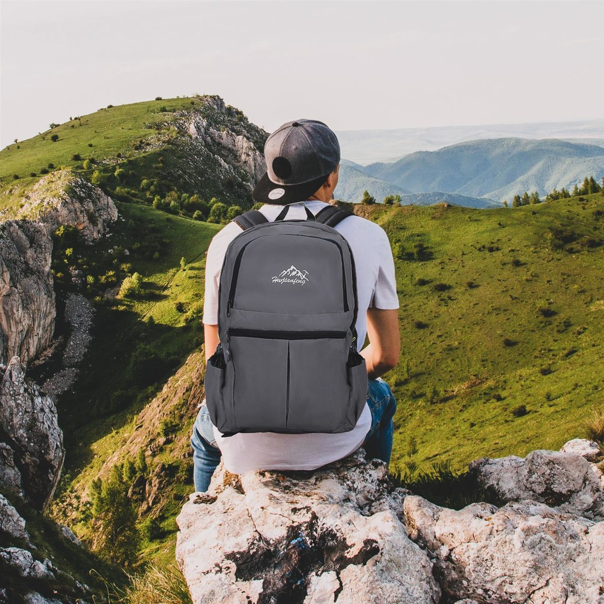 Ein Mann sitzt auf einem Felsen und betrachtet Berge mit Rucksack.