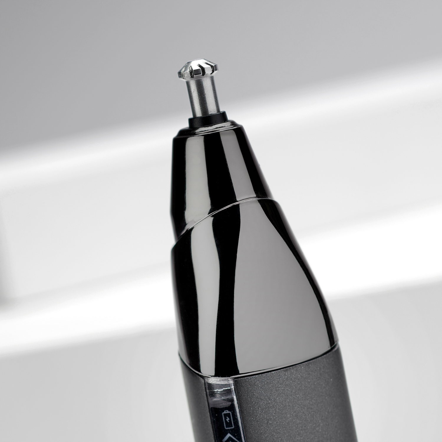 Zbliżenie czarnej maszynki do strzyżenia włosów w nosie. Górna część ma srebrną końcówkę i błyszczący czarny korpus.