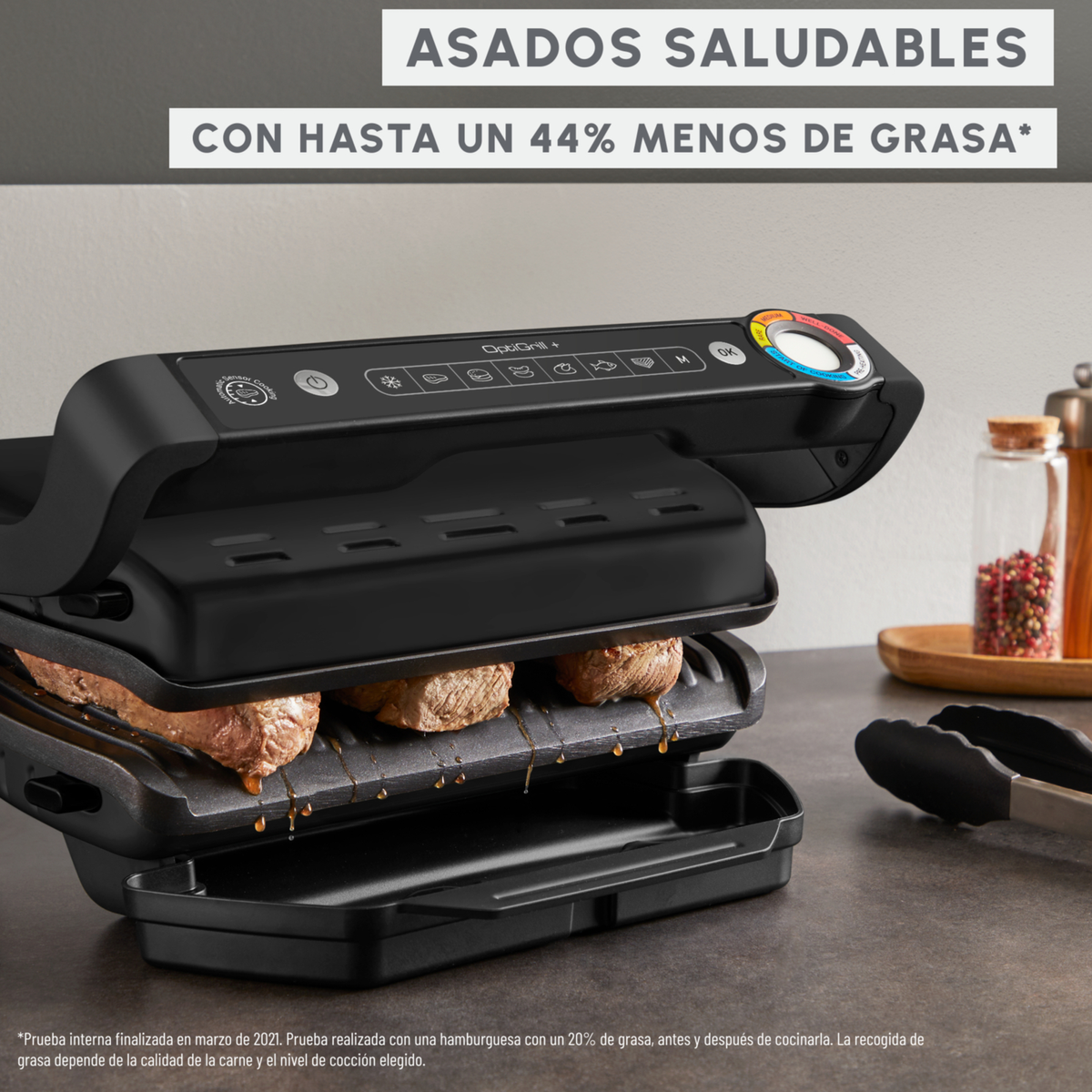 Parrilla negra con comida cocinándose, texto 'asados saludables' con menos grasa, en una encimera.
